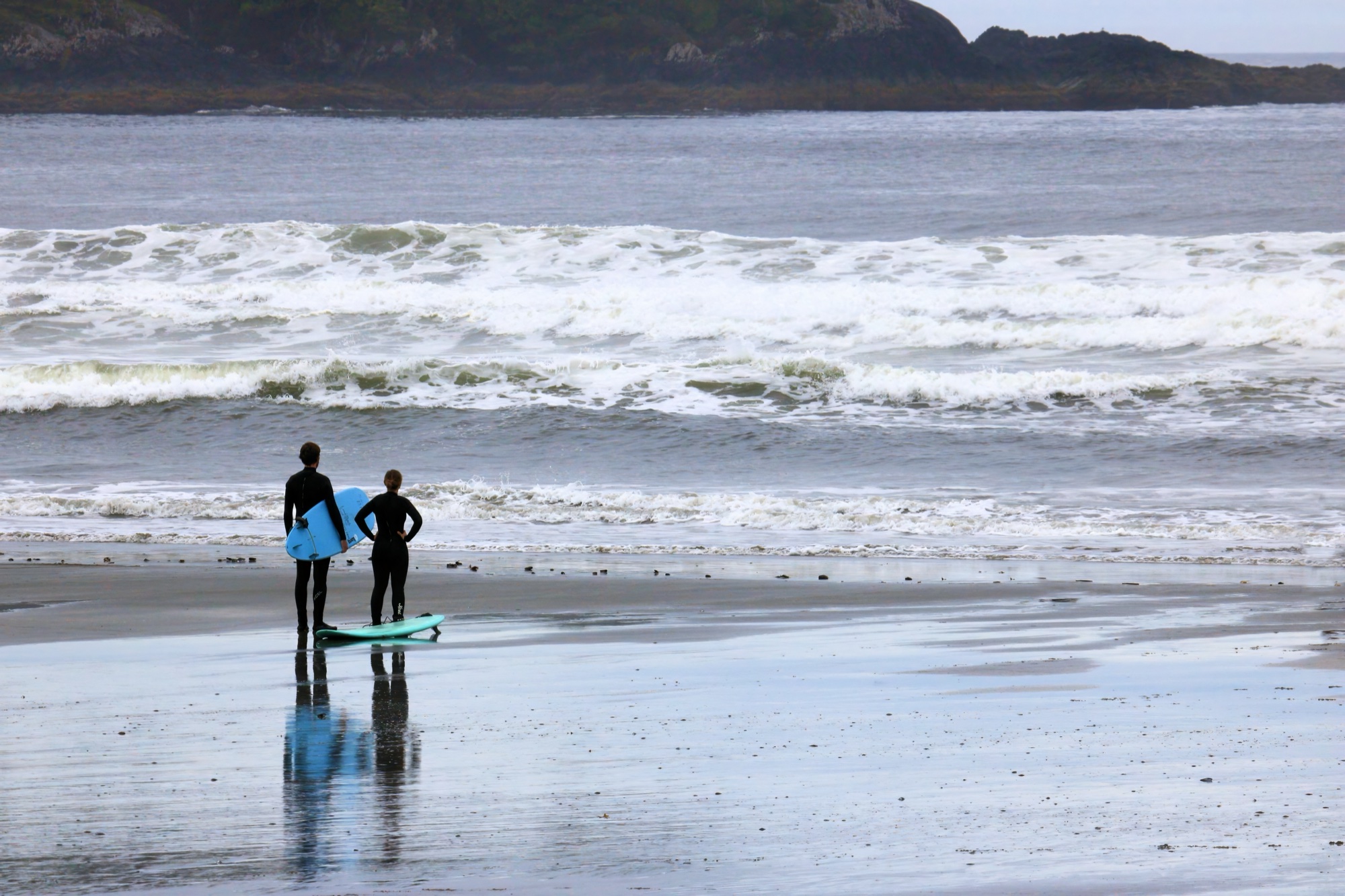 Pár surfařů na Cox Bay pláži v Tofinu, Vancouver Island