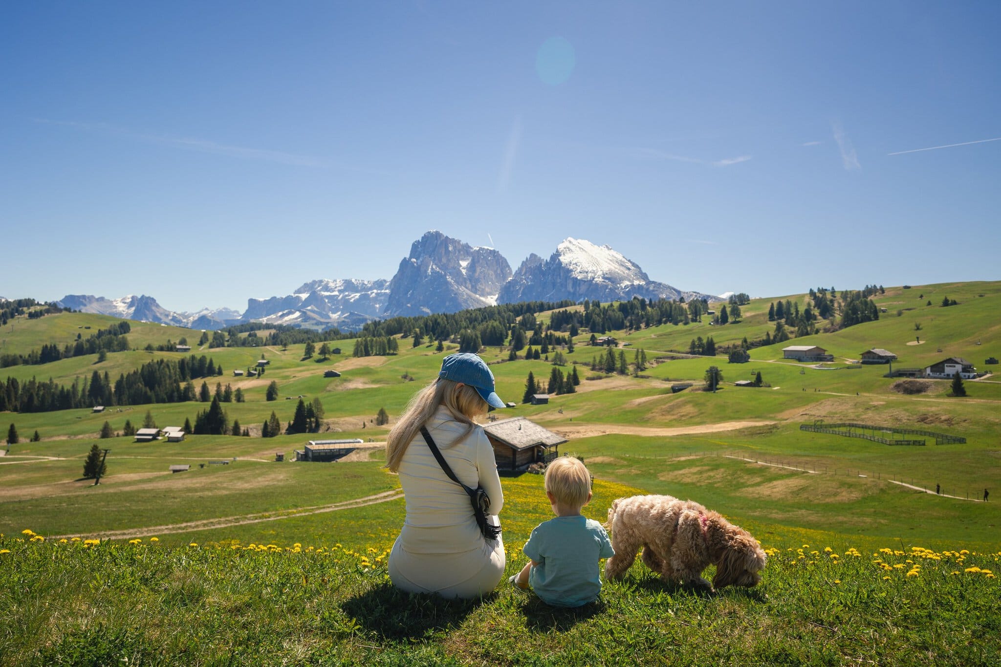 Alpe di Siusi (Seiser Alm), Dolomiti: 12 cose da vedere e da fare 1 Famiglia con cane che si riposa sul pascolo con vista sul Sassolungo