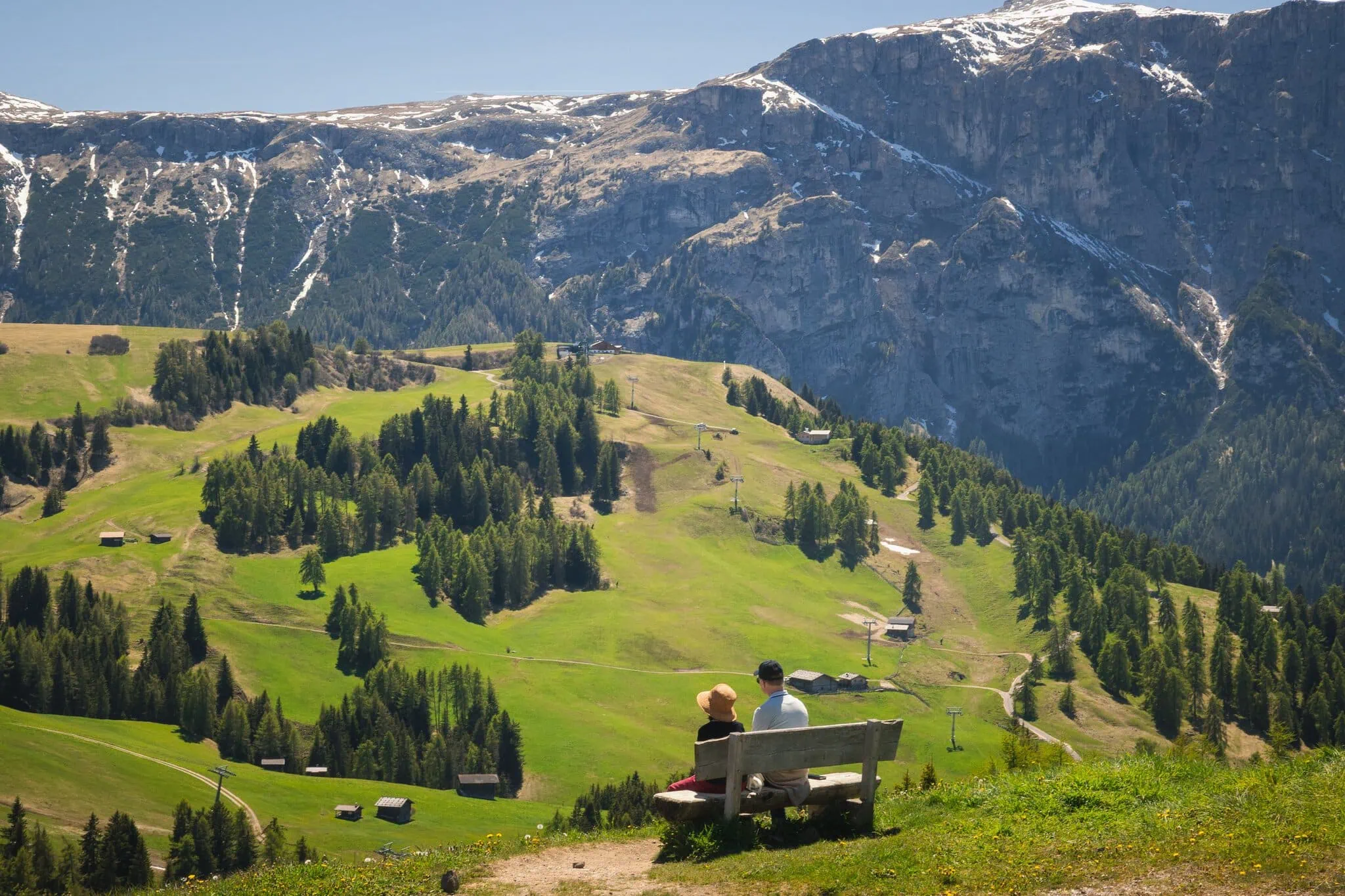 Pár na lavičce s výhledem na rozlehlou alpskou louku Seiser Alm