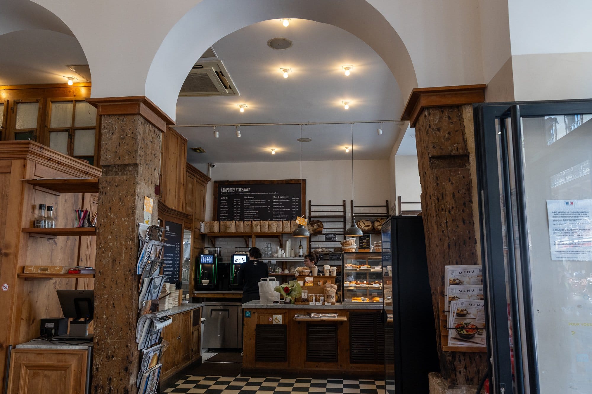 Ce să mănânci la Paris: Ghid foodie complet 2026 (bistrouri, Michelin, scena vegetariană) 15 Cafenea pariziană cochetă cu interior din lemn și vitrină cu patiserie
