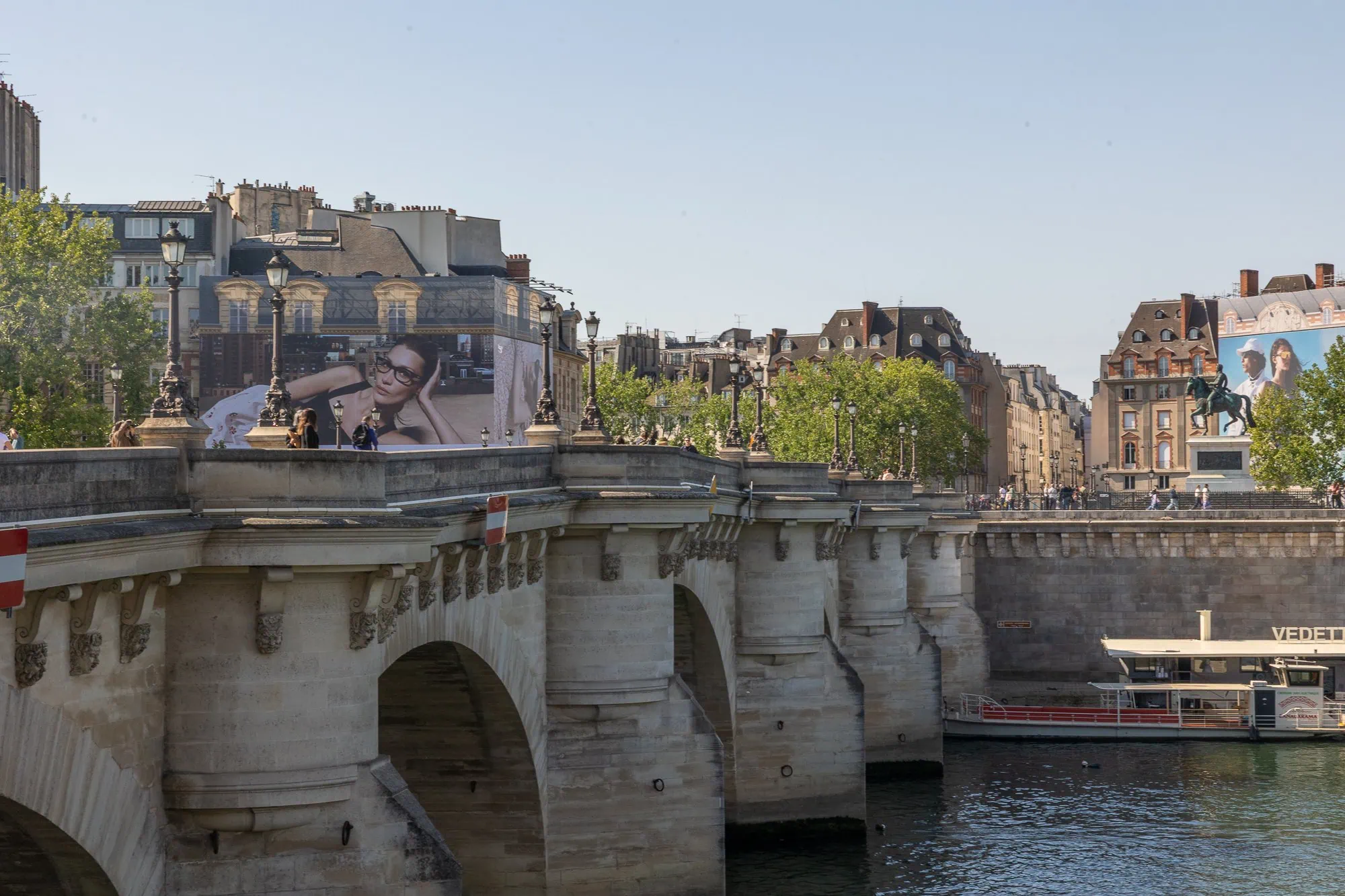 Historický Pont Neuf přechází řeku Seinu v Paříži se zajímavými budovami v pozadí