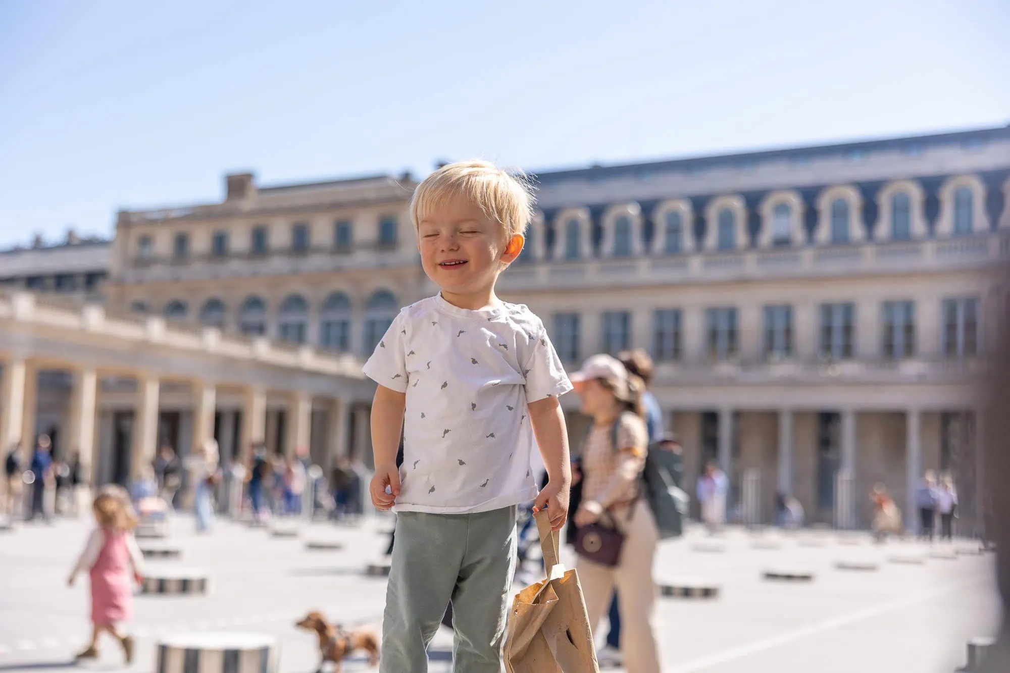 Usměvaný chlapec stojí na náměstí Palais Royal v Paříži