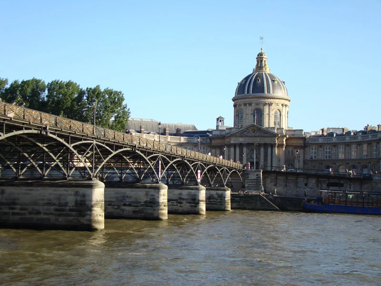 Pěší most Pont des Arts přes Seinu s budovou Institut de France
