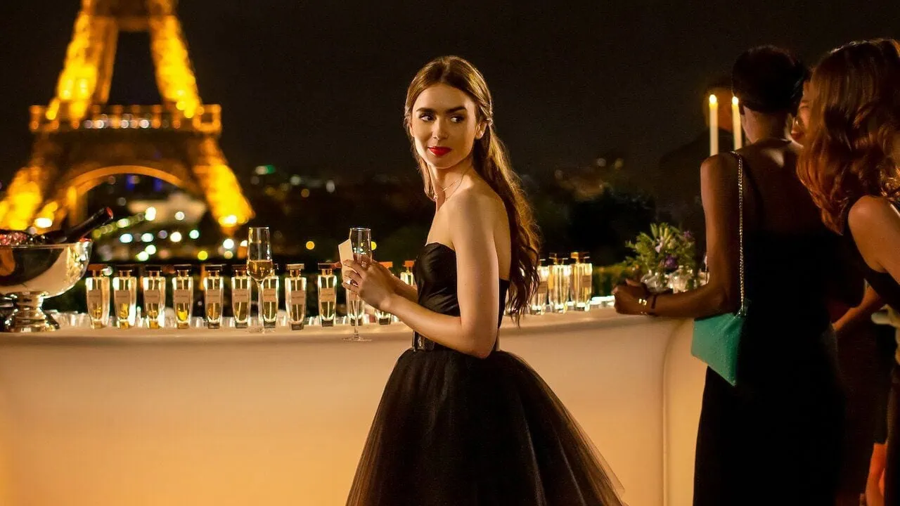 Emily na večírku s nasvícenou Eiffelovou věží v pozadí, seriál Emily in Paris