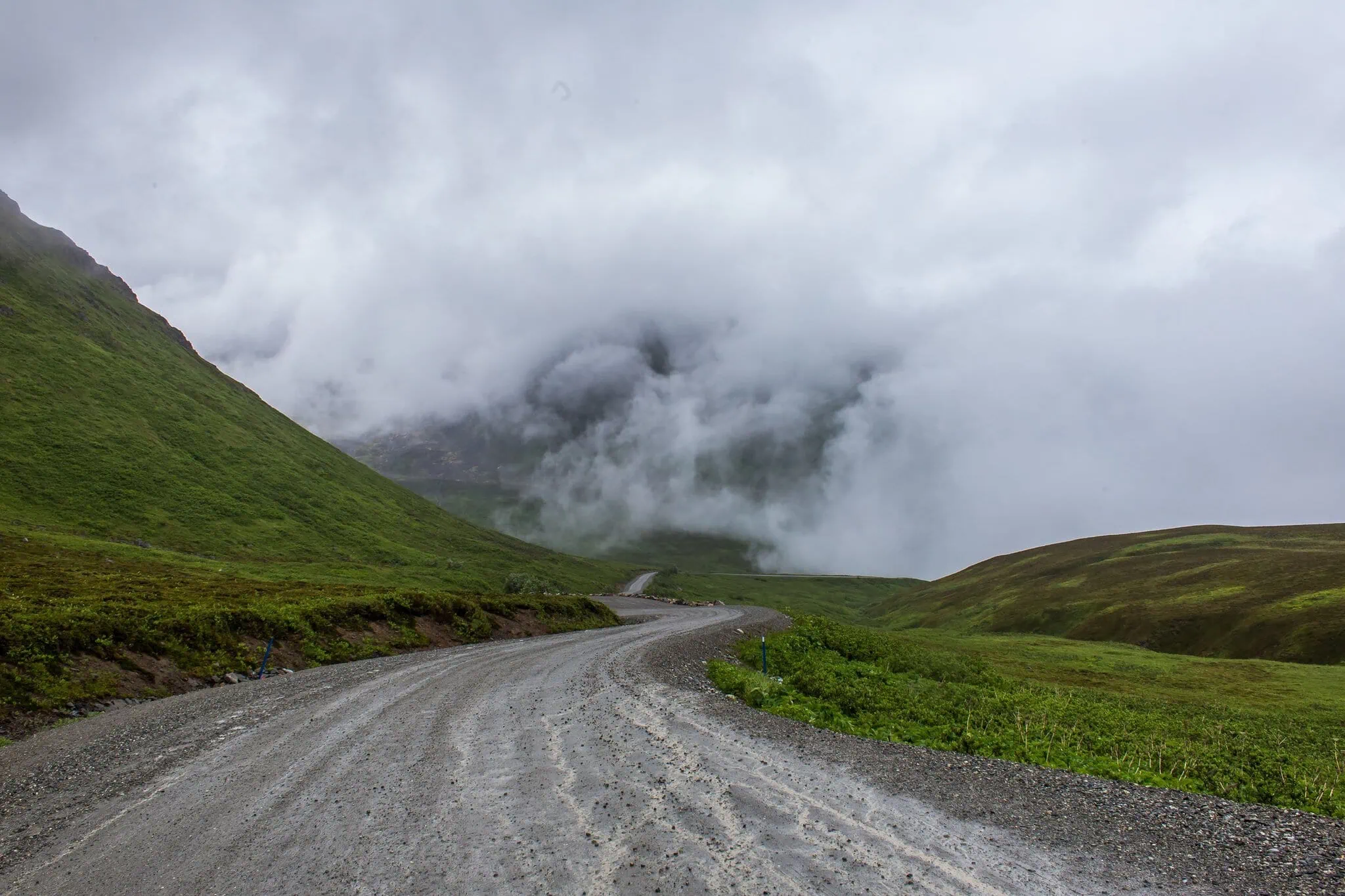 Carretera entre la niebla en Hatcher Pass — el tiempo típico de Alaska