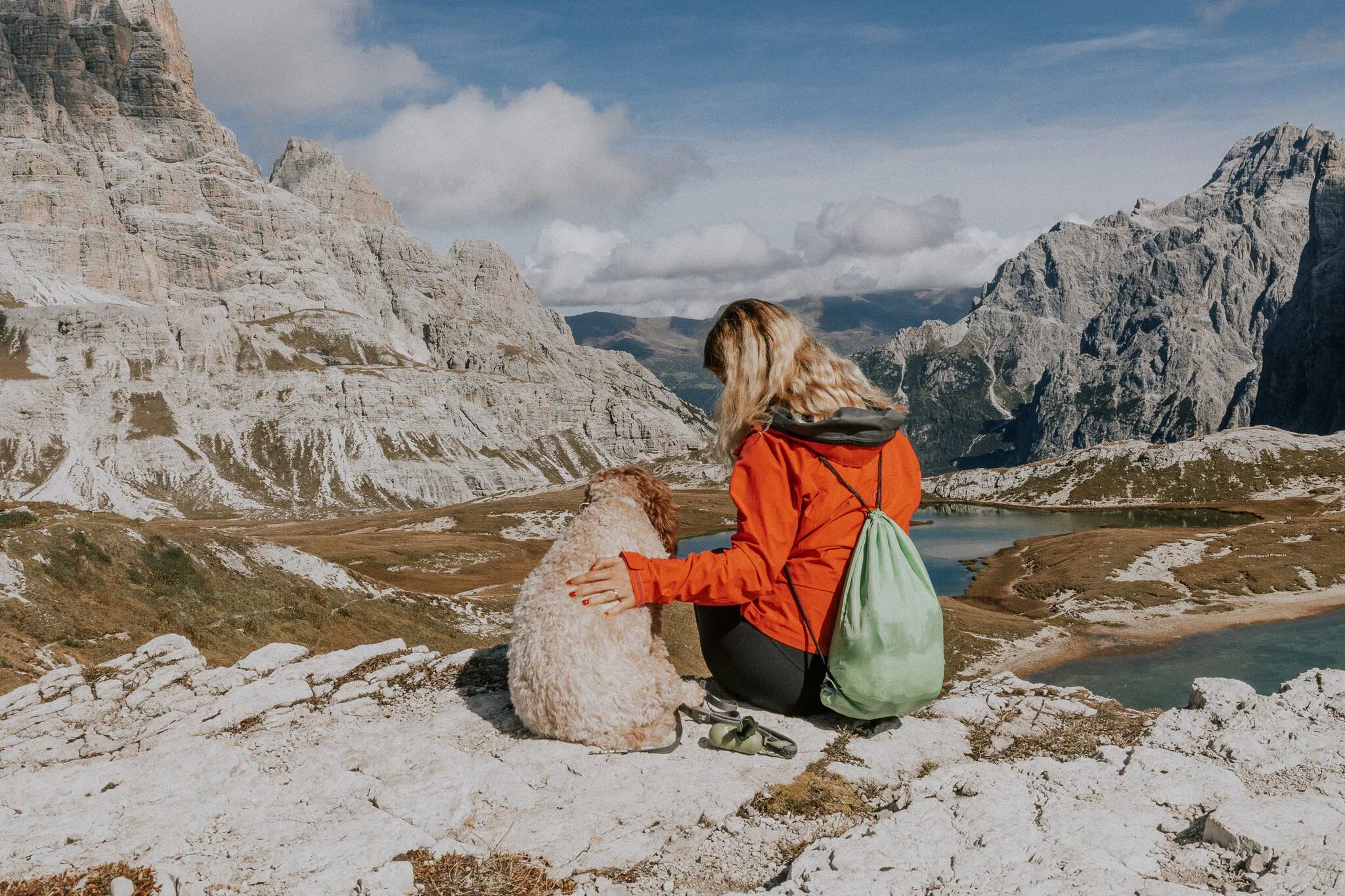 Turista přichází po stezce k jezeru mezi skalními štíty
