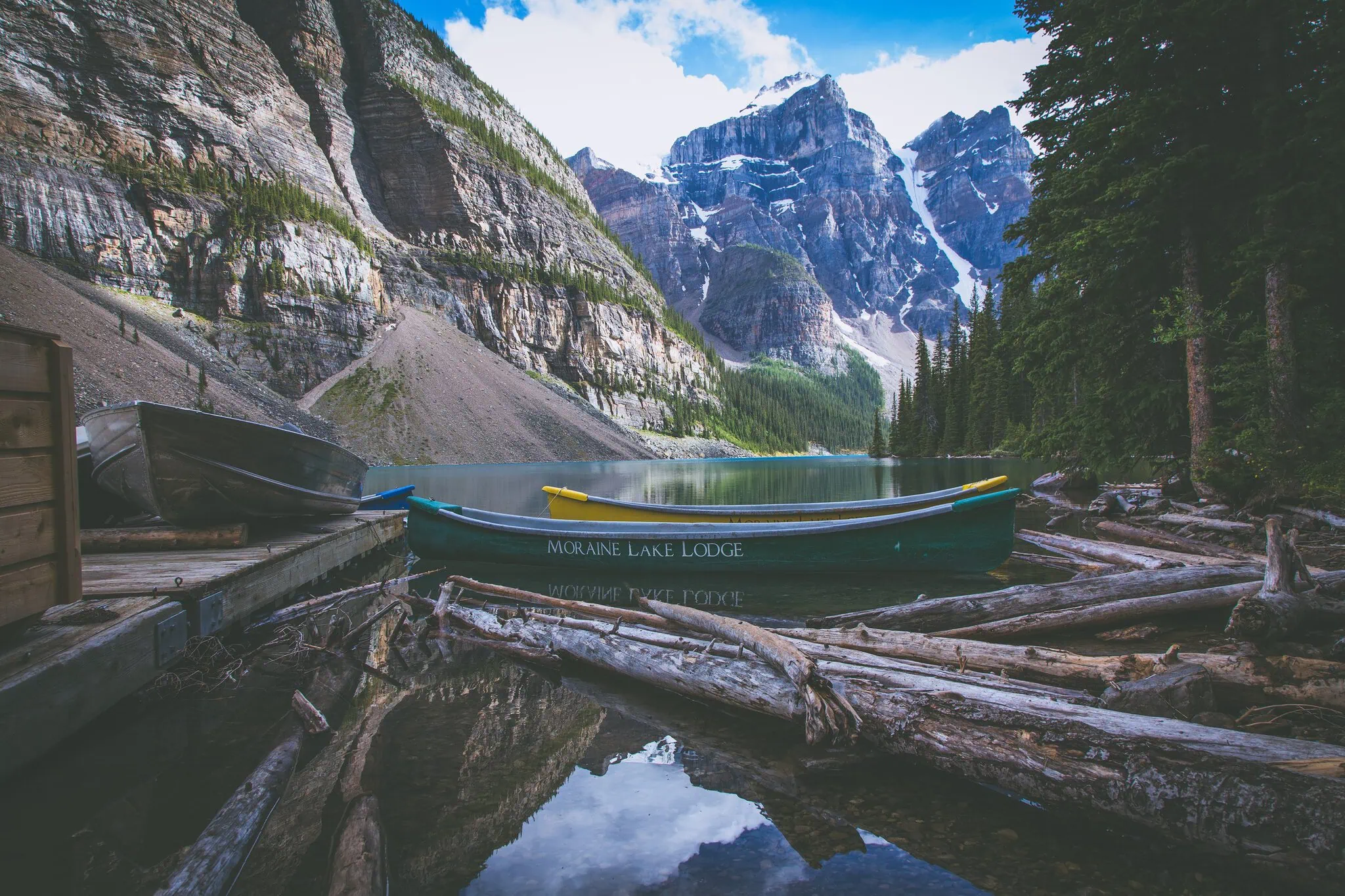Kanoe s nápisem Moraine Lake Lodge mezi naplavenými kmeny