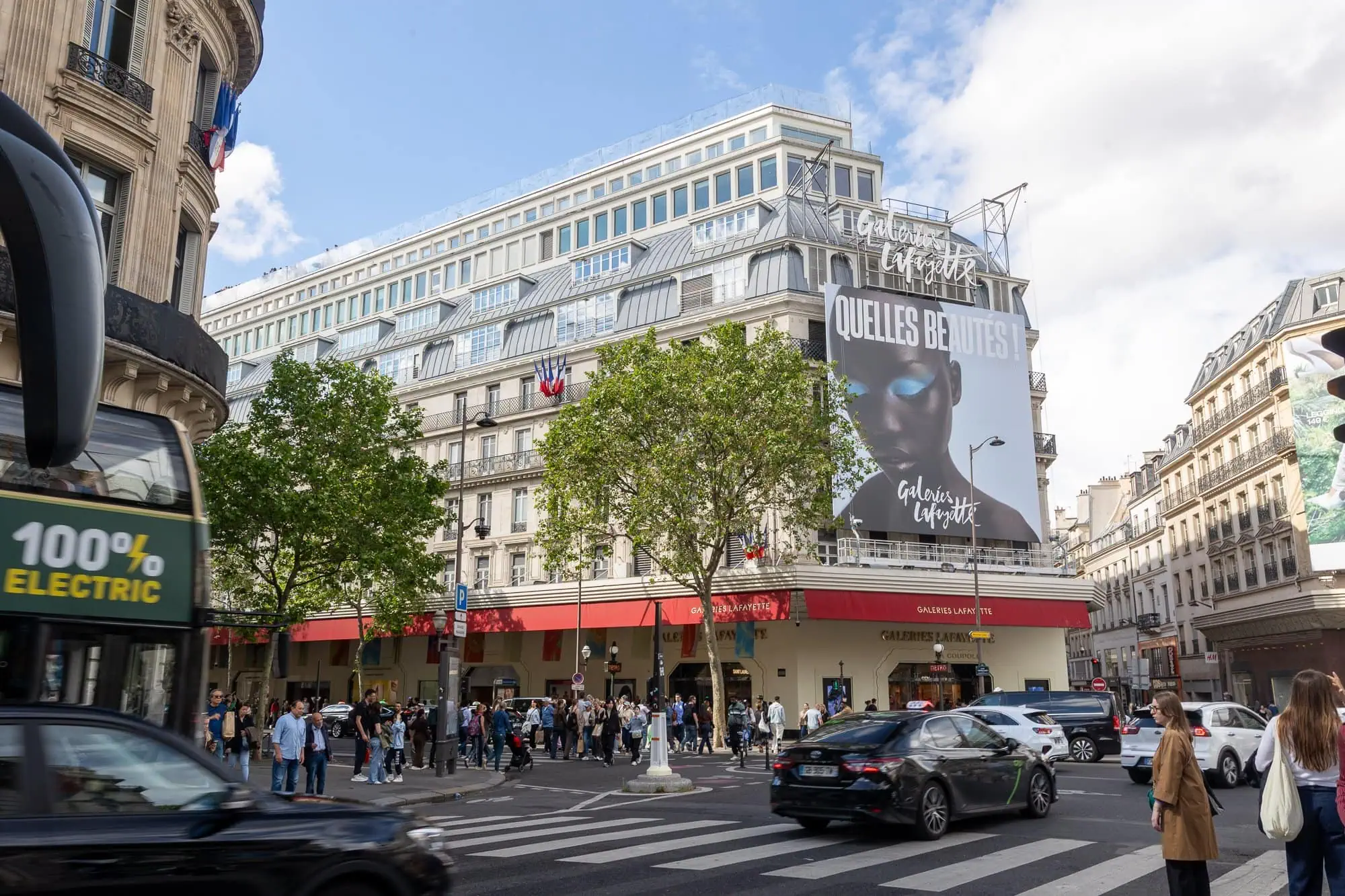 Elegantní budova Galeries Lafayette s velkým transparentem a davem návštěvníků