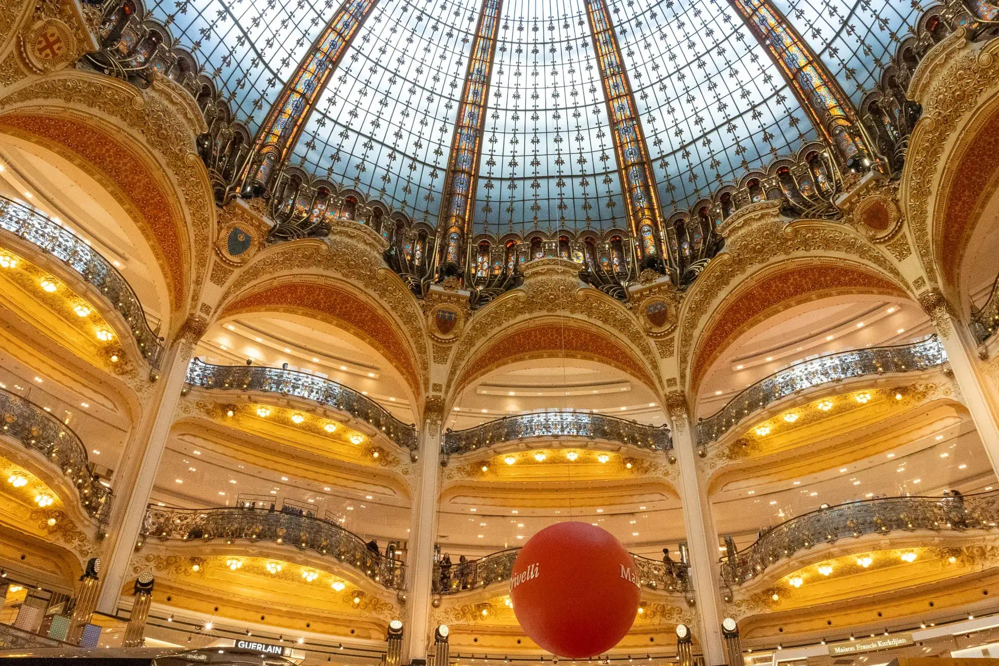 Skleněná kupole Galeries Lafayette se červenou koulí a zlatými oblouky