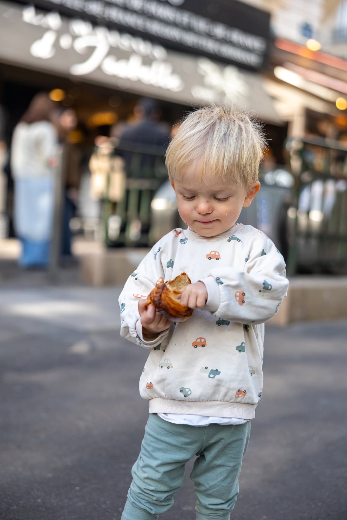 38 de lucruri de văzut la Paris: ghid complet 2026 (+ ce să NU faci și itinerarii de 2–5 zile) 30 Copilaș mâncând un croissant proaspăt dintr-o brutărie pariziană