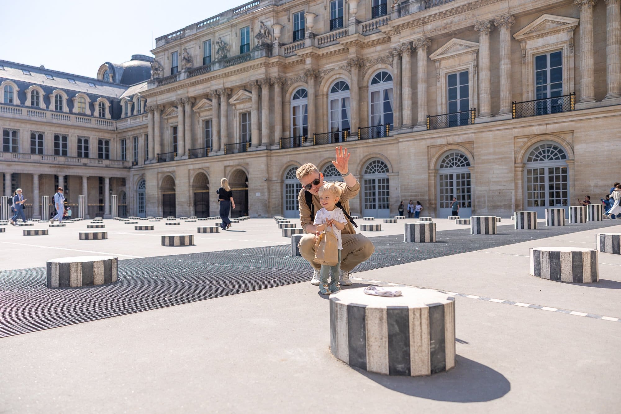 Paris cu copii: Ghidul complet pentru un city break în familie (la ce să te aștepți cu căruciorul) 3 Un bărbat se joacă cu un copil mic în curtea Palais Royal din Paris