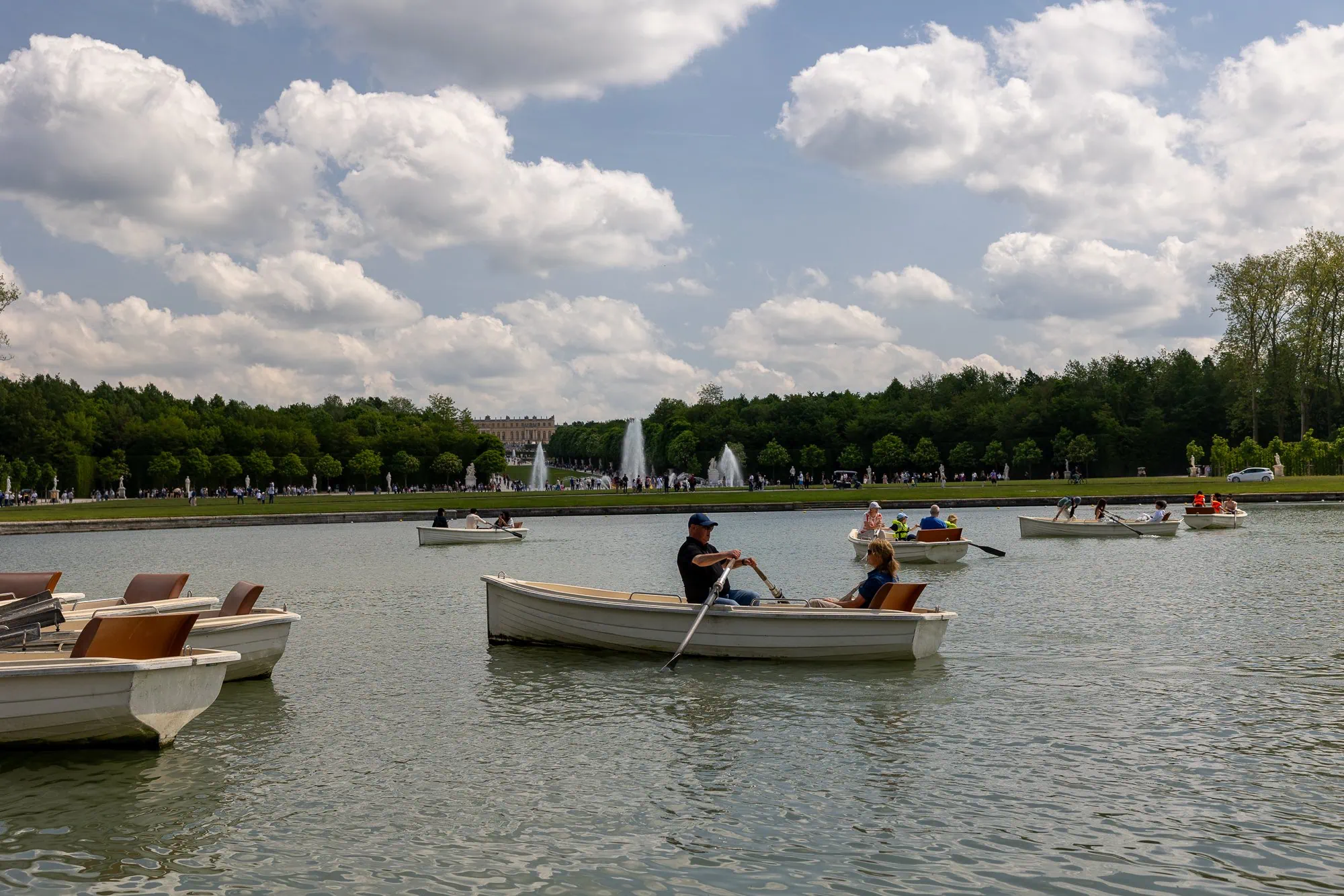 Paříž s dětmi: Kompletní průvodce rodinnou Paříží (na co se připravit s kočárkem) 13 Rekreační člunky plují na rybníku u paláce Versailles s fontánami v pozadí