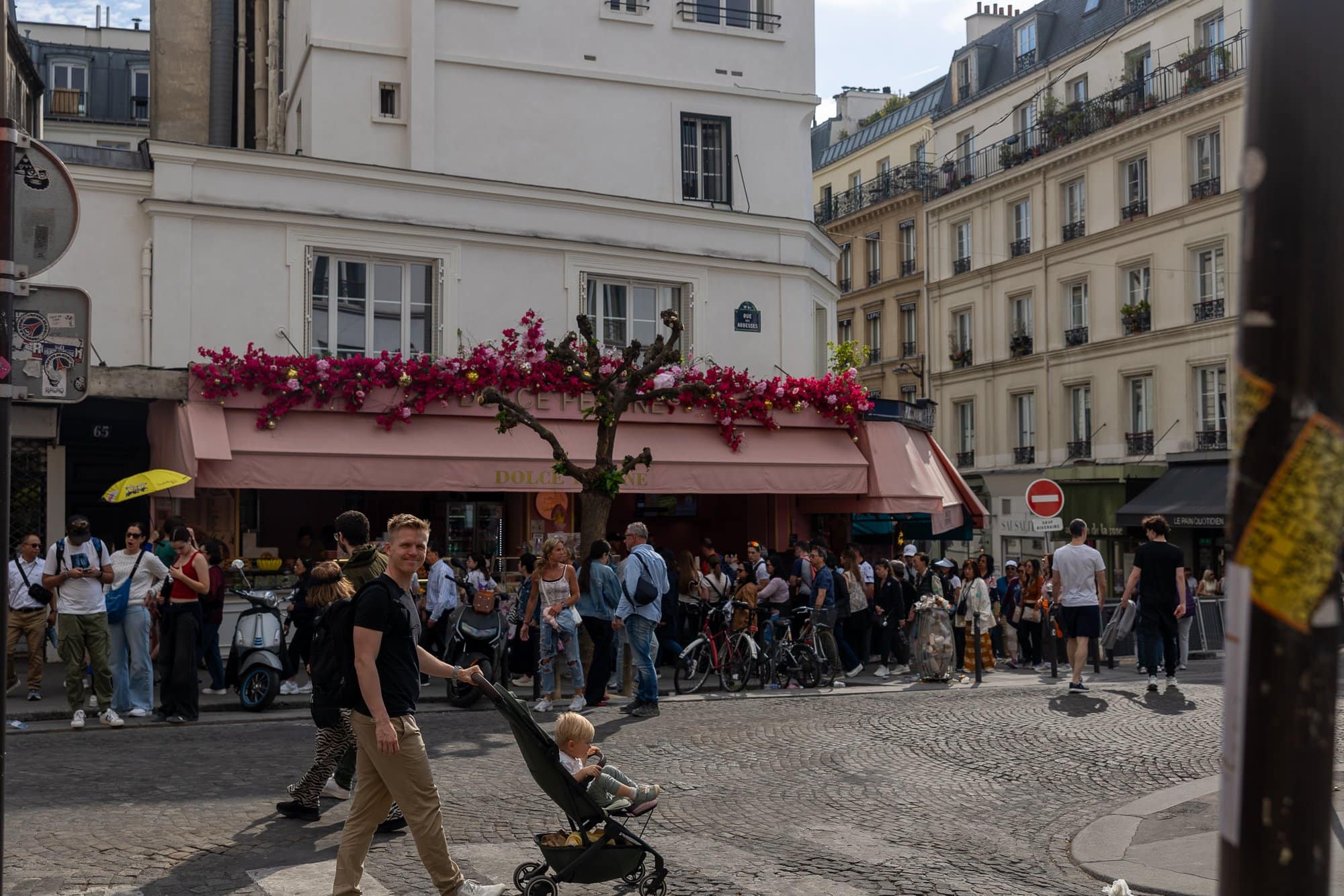 Paris cu copii: Ghidul complet pentru un city break în familie (la ce să te aștepți cu căruciorul) 10 O stradă pariziană aglomerată, cu flori și magazine, plină de turiști