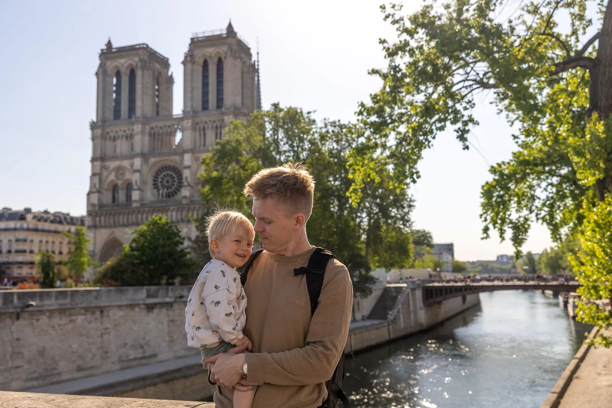 Otec drží malého syna před Notre-Dame se Seinou