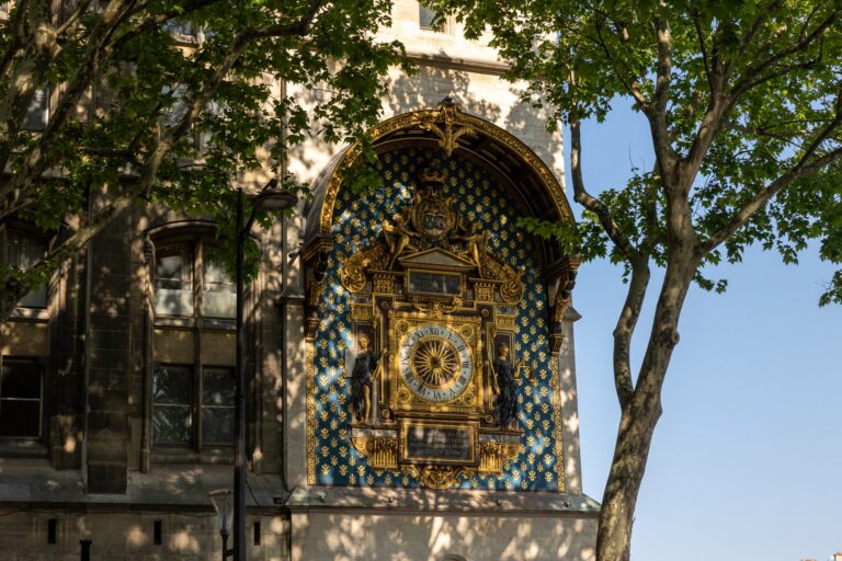 Luxusní art nouveau hodiny s zlatou výzdobou na modré fasádě