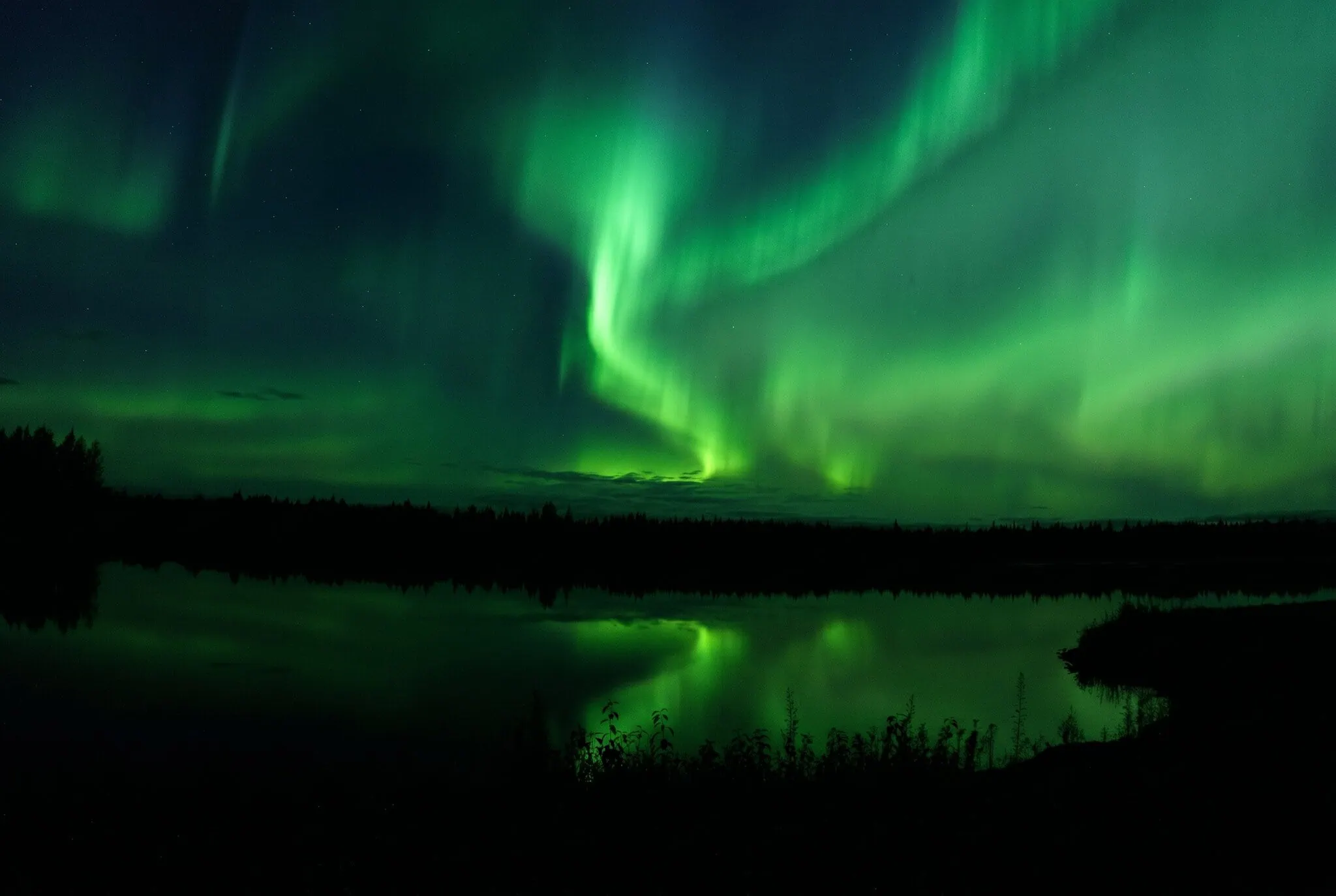 Aurora boreal verde reflejándose en un lago de Alaska