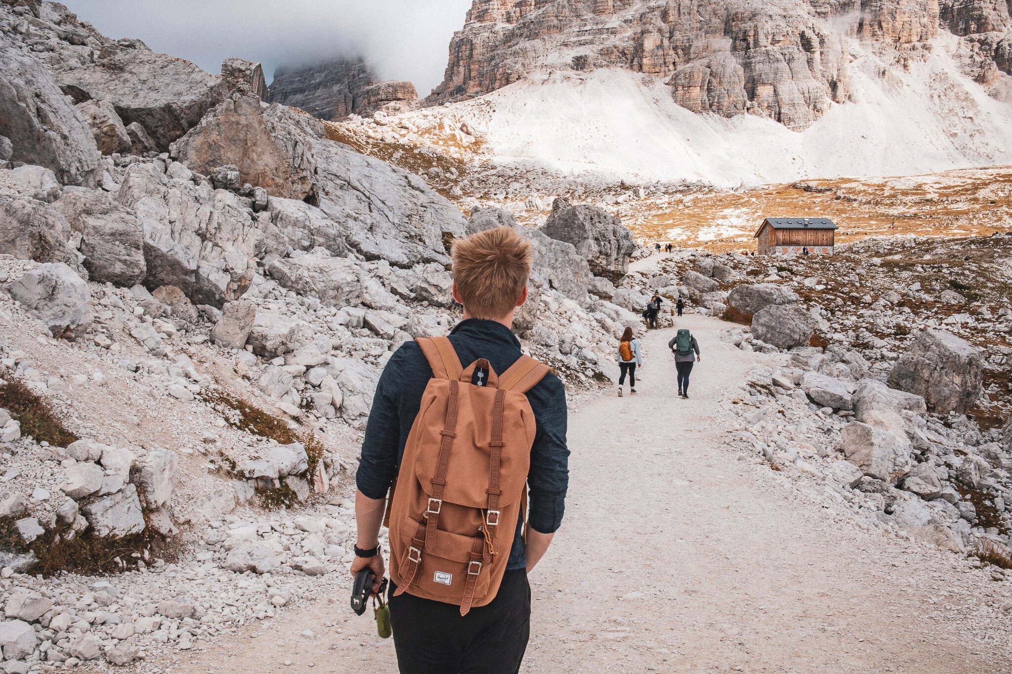 Drei Zinnen in Italien: 12 Tipps, was man sehen und unternehmen kann 8 Wanderer mit Rucksack auf dem Trekking-Pfad zwischen den Felswänden der Drei Zinnen