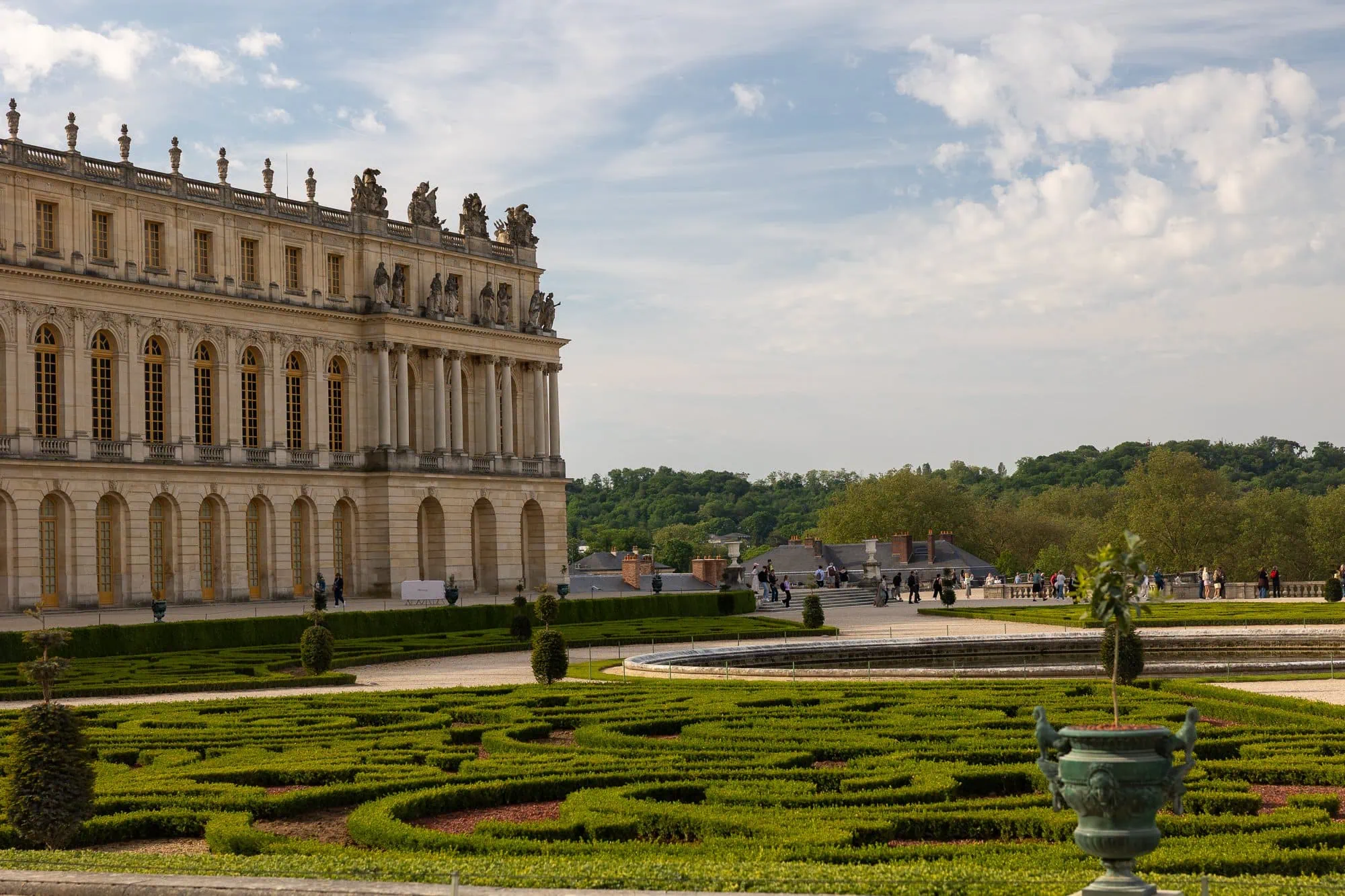 Versailleský palác s kolonnádou a formální zahradou se živými ploty a bazénem