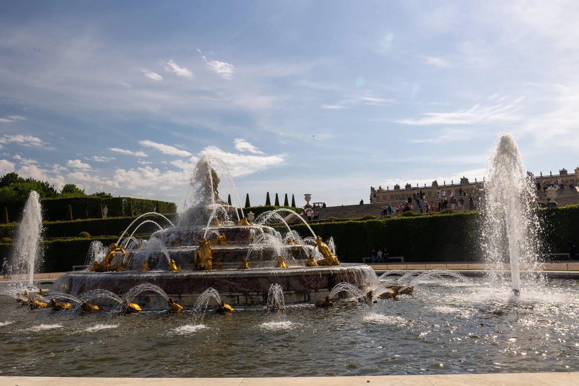 Barokní fontána s zlatými sochami a vodními tryskami v Versailles