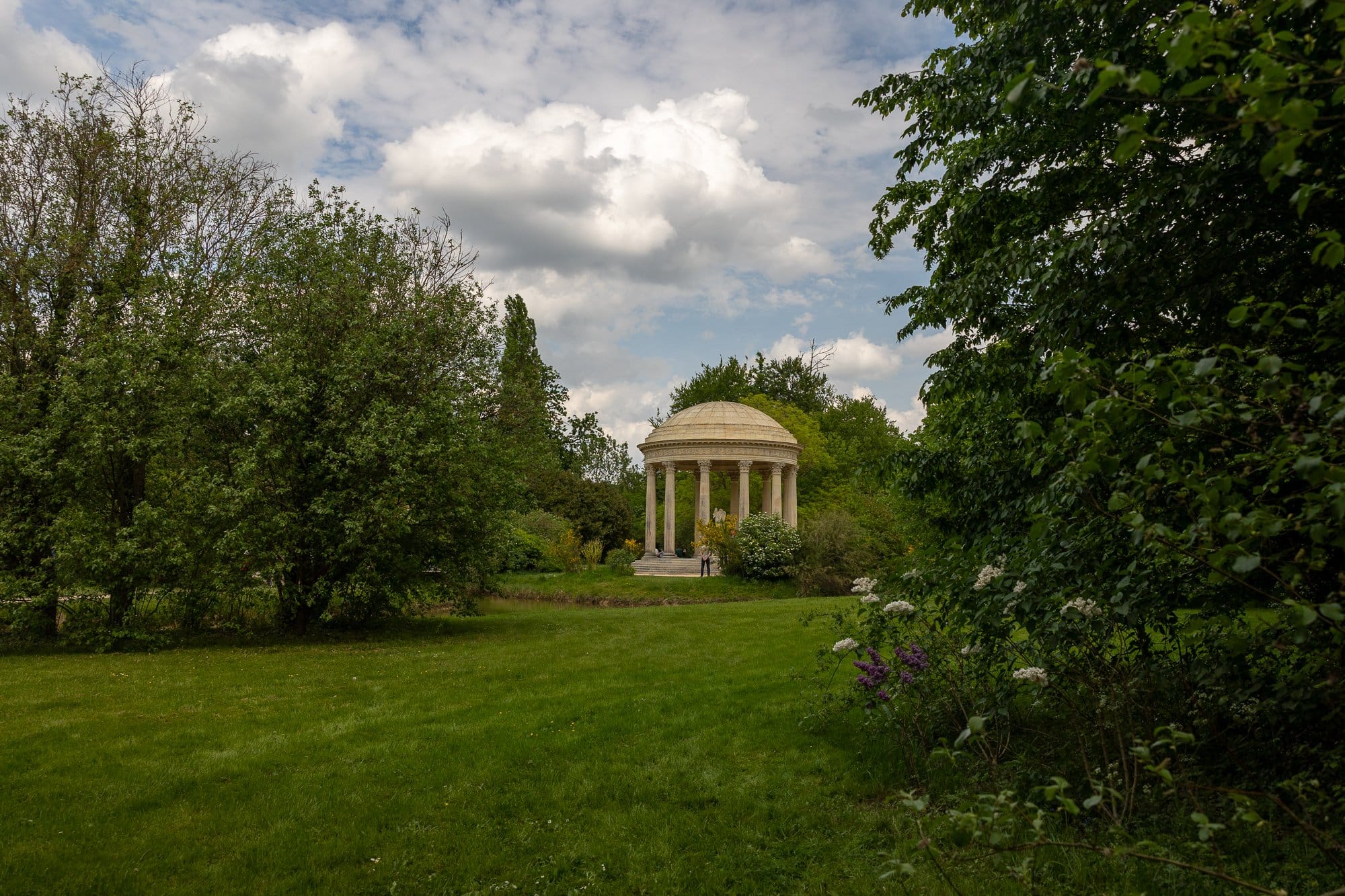 Utflykter från Paris: Versailles, Giverny, Chantilly och Fontainebleau 4 Vitt runt nyklassicistiskt tempel med kolonnad i en park omgiven av grönska