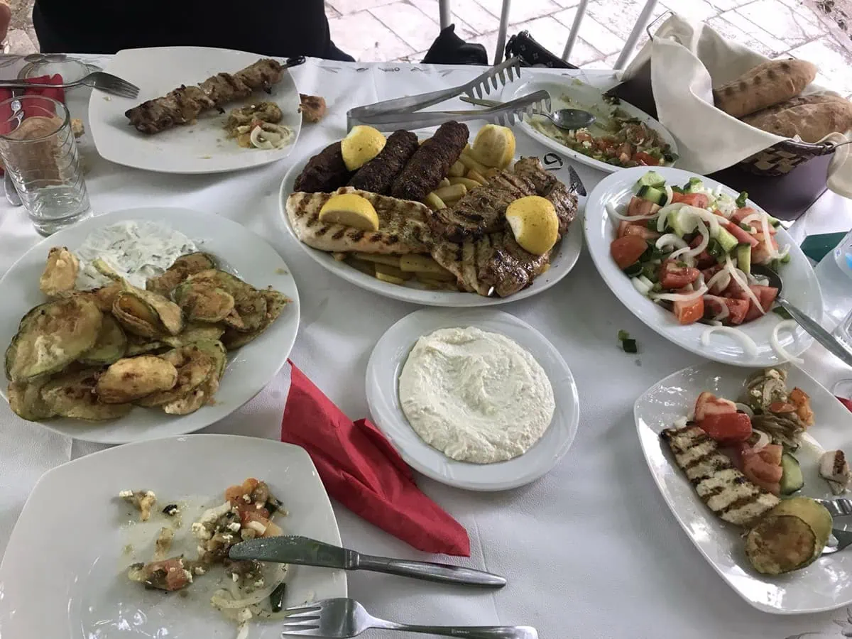 Stół pełen greckich specjałów w tawernie: souvlaki, sałatki i tzatziki