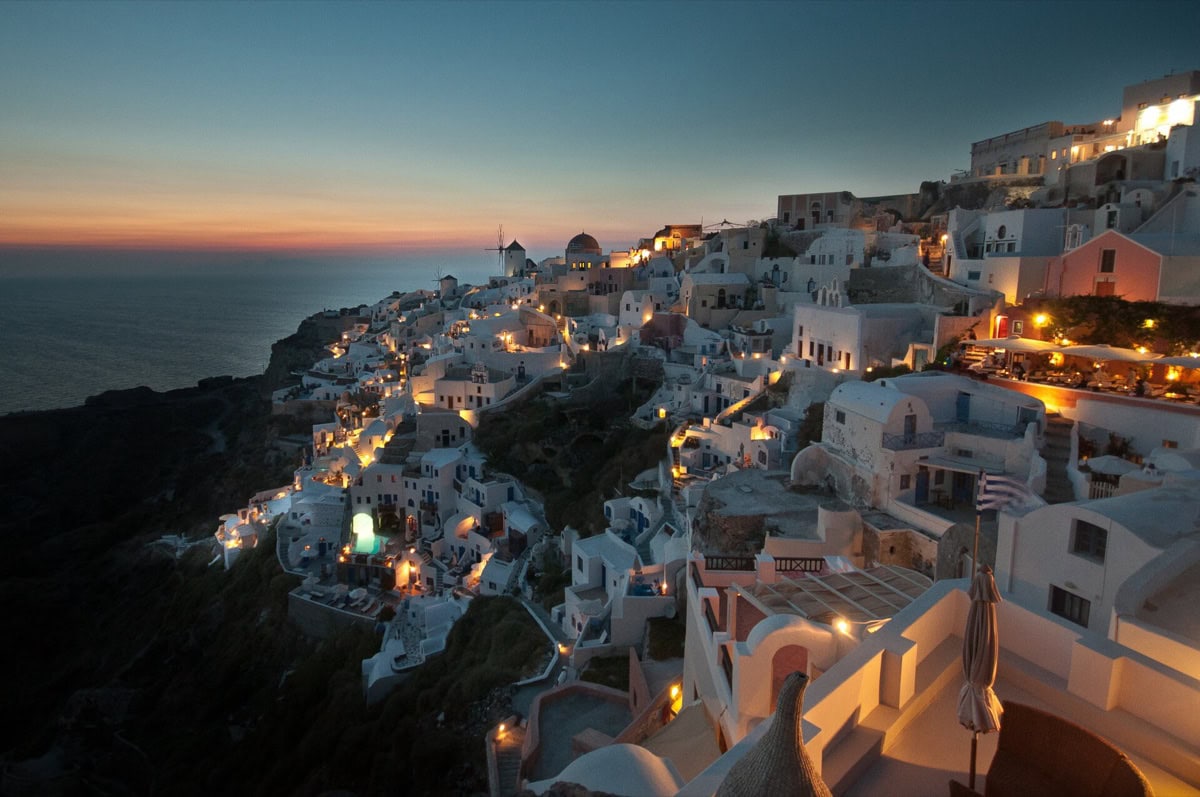 Romantický západ slunce nad kalderou Santorini s klidným mořem a teplými barvami oblohy