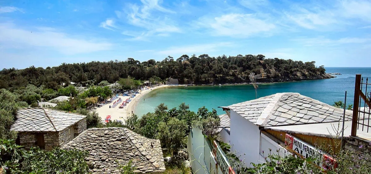 Panorama över den dubbla viken Aliki med turkost vatten, sandstrand och stenhus på halvön Thassos