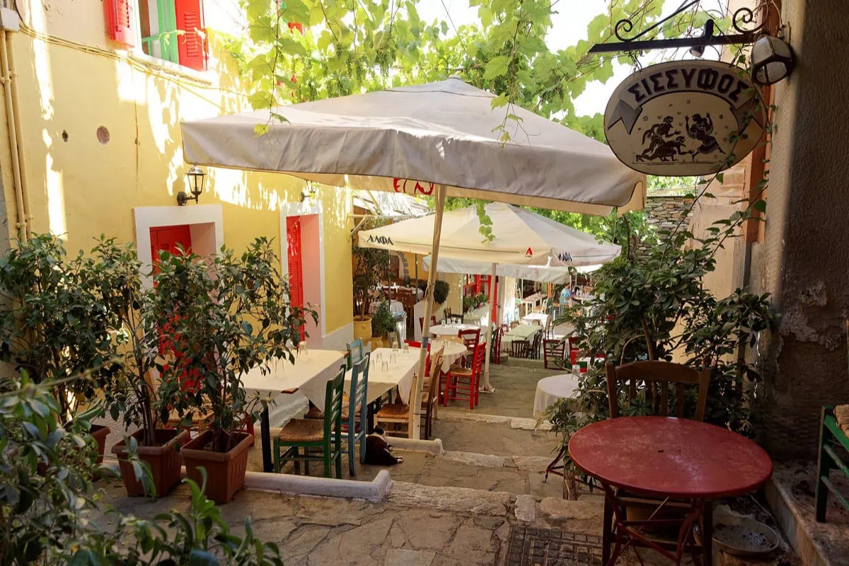 Stradina stretta nel quartiere ateniese di Plaka con taverne e tavolini all'aperto