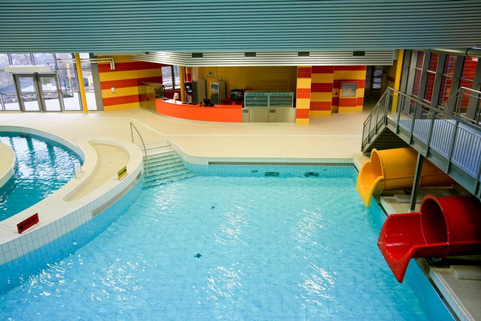 Die besten Aquaparks in Tschechien: 13 Tipps für Familien 2026 7 Überdachtes Becken und orangefarbene Rutsche des Aquacentrum Šutka in Prag