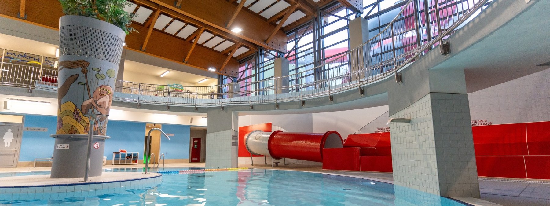 Die besten Aquaparks in Tschechien: 13 Tipps für Familien 2026 11 Überdachtes Becken und rote Rutsche des Aquaparks Kohoutovice in Brünn