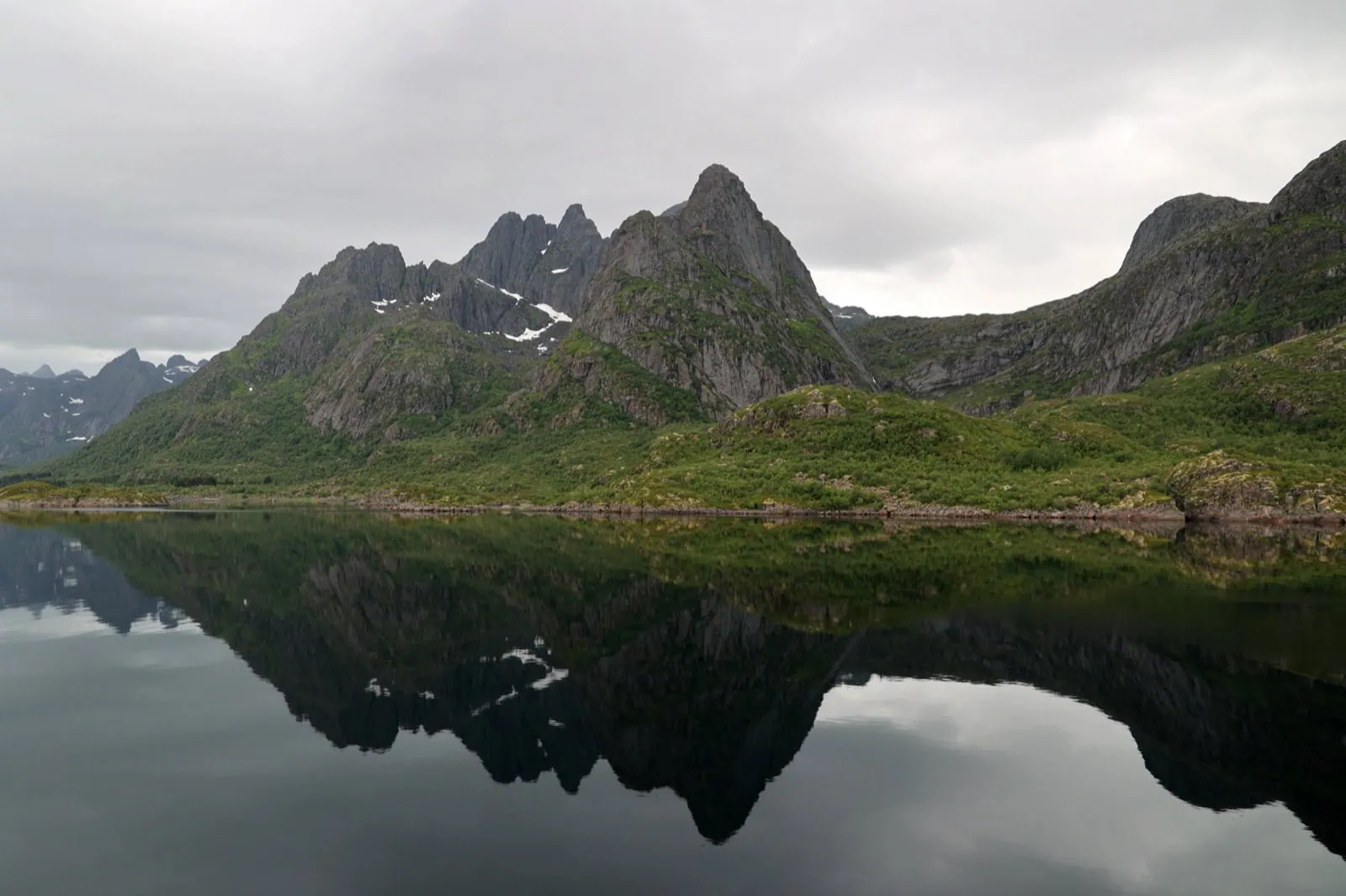 Strmé štíty zrcadlící se v klidném fjordu