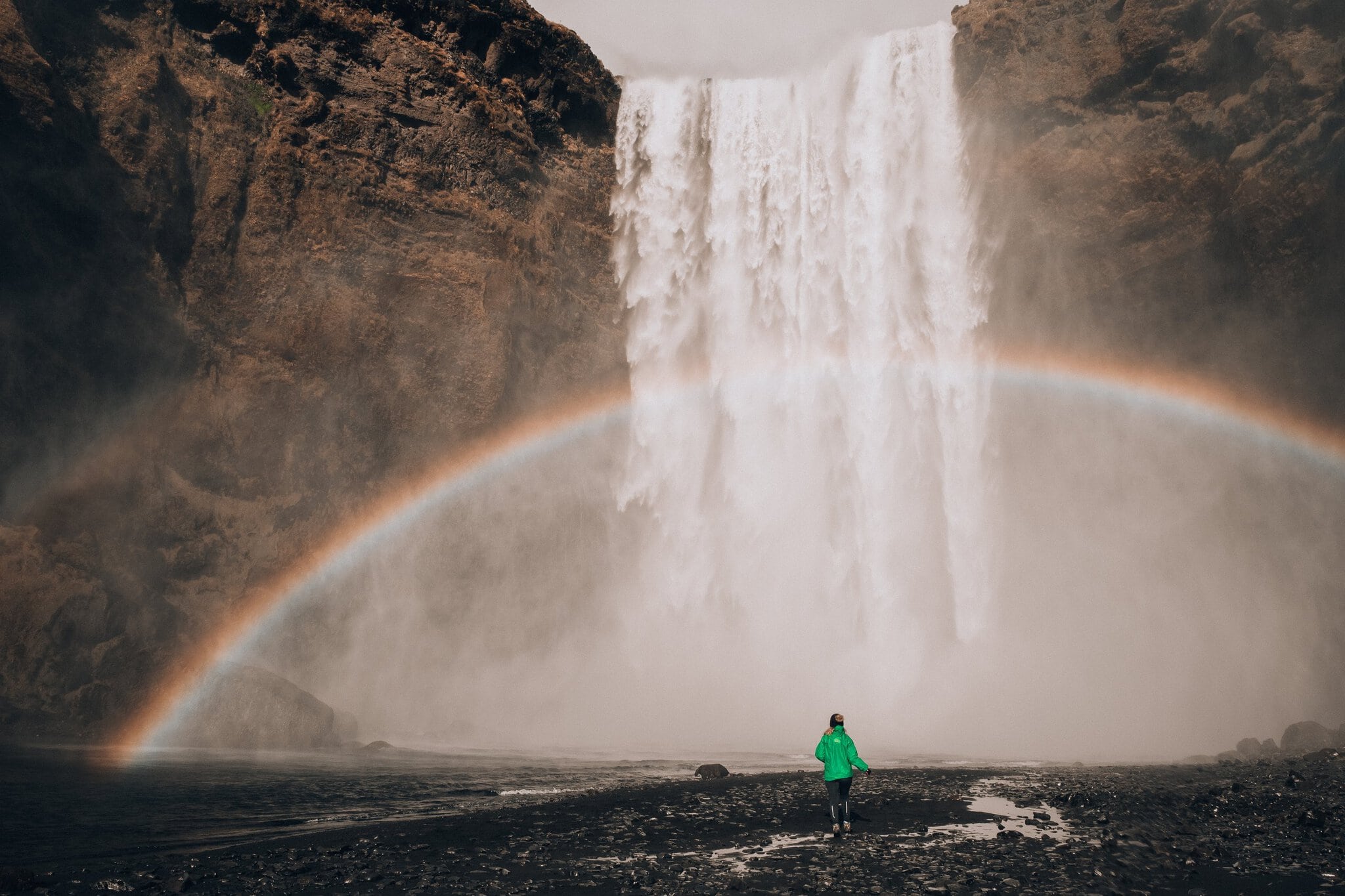 Costa sur de Islandia: 12 cosas que ver y hacer 7 Mujer frente a la cascada Skógafoss con un arcoíris en Islandia