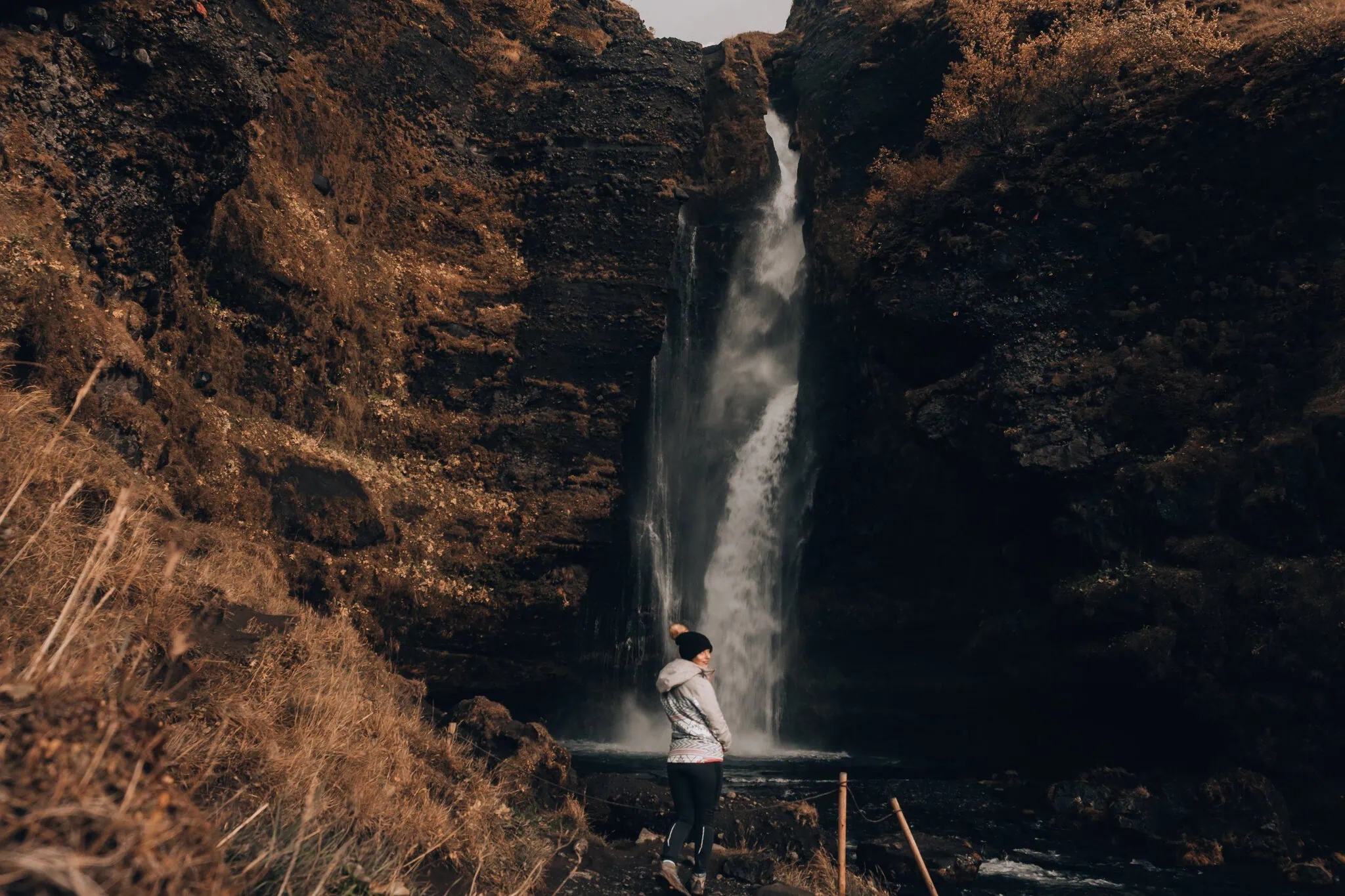 Zuidkust van IJsland: 12 tips voor wat je moet zien en doen 6 Vrouw bewondert de waterval Gljúfrabúi verborgen in een rotsspleet