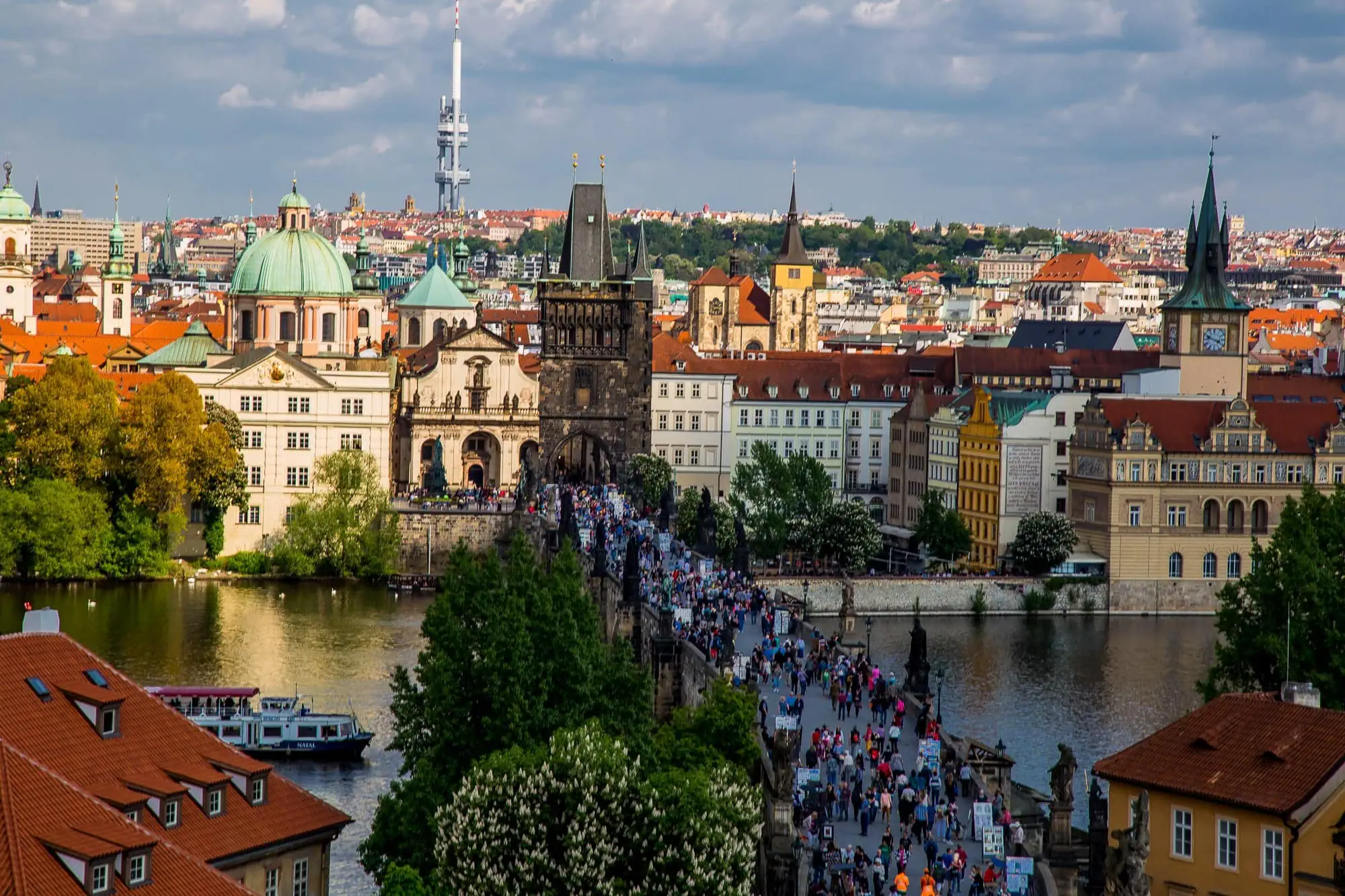 Co vidět v Praze: 100+ tipů na památky, kavárny, restaurace (2026) 6 Karlův most plný návštěvníků s Vltavou při pohledu z věže