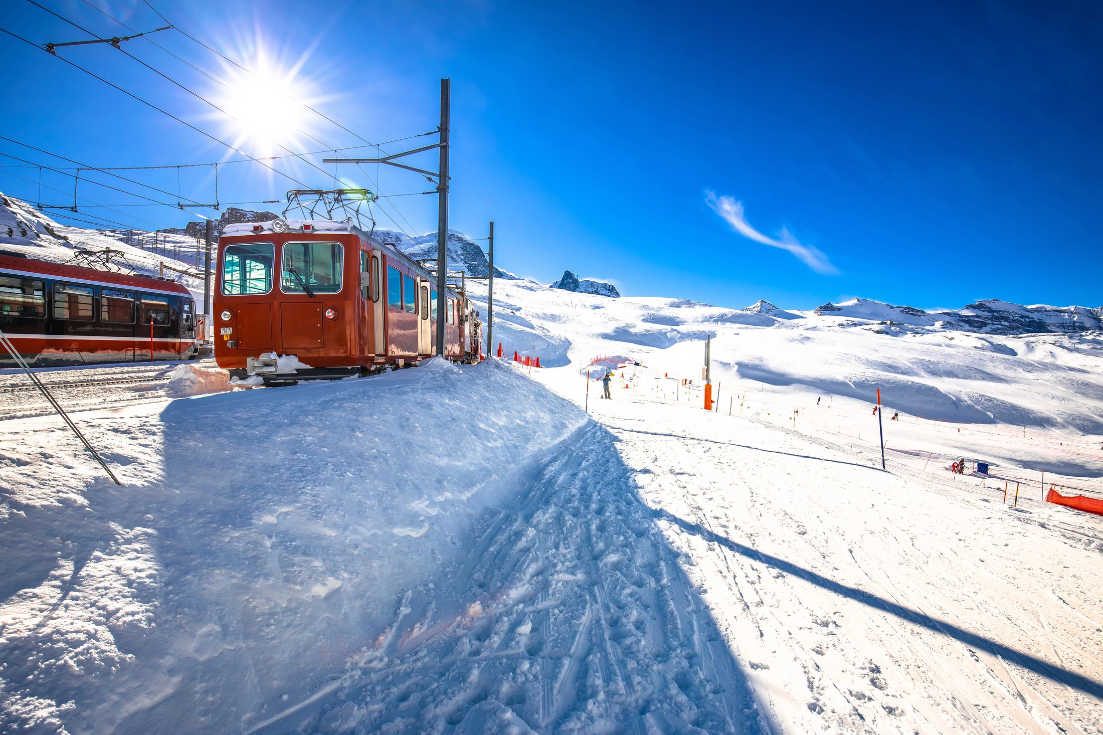 Tåg i Schweiz: Glacier Express, Bernina Express & co + priser 2026 2 Rött bergståg på Gornergratbanan i solsken över ett snötäckt landskap