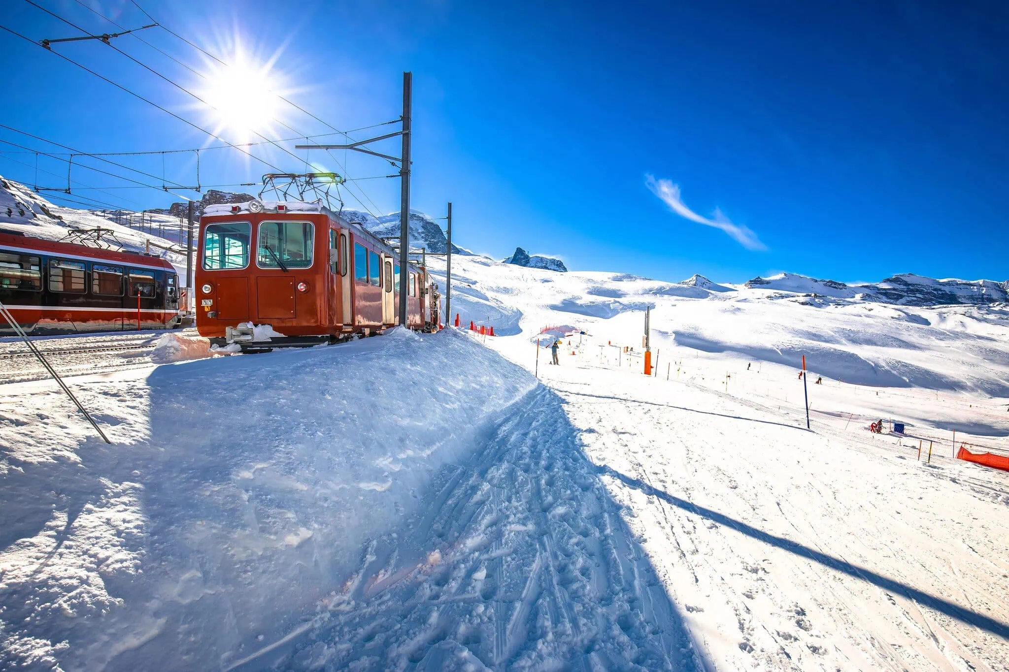 Svájc vonattal: Glacier Express, Bernina Express és társai + árak 2026-ban 2 A Gornergrat-vasút piros hegyi vonata a napsütésben, havas táj felett