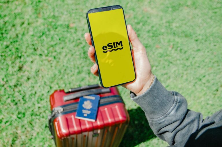Telefon s aktivní eSIM, cestovní pas a kufr připravené na cestu