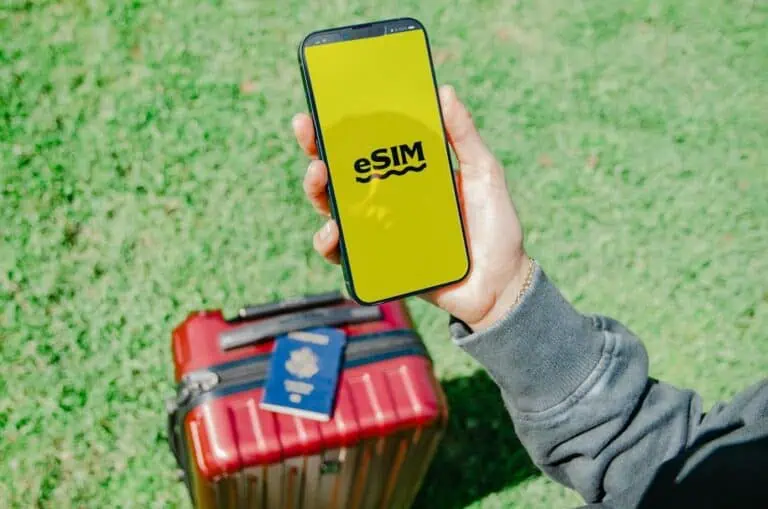 Telefon s aktivní eSIM, cestovní pas a kufr připravené na cestu