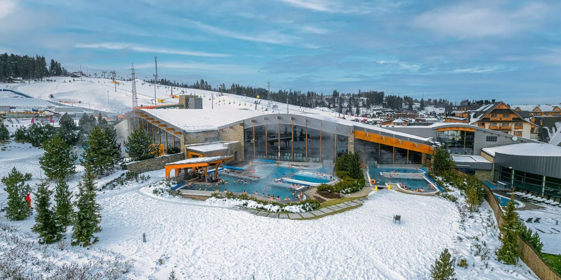 Les meilleurs thermes en Pologne : 8 adresses près de la frontière et dans les Tatras en 2026 1 Bassins thermaux extérieurs de Terma Bania dans un paysage enneigé