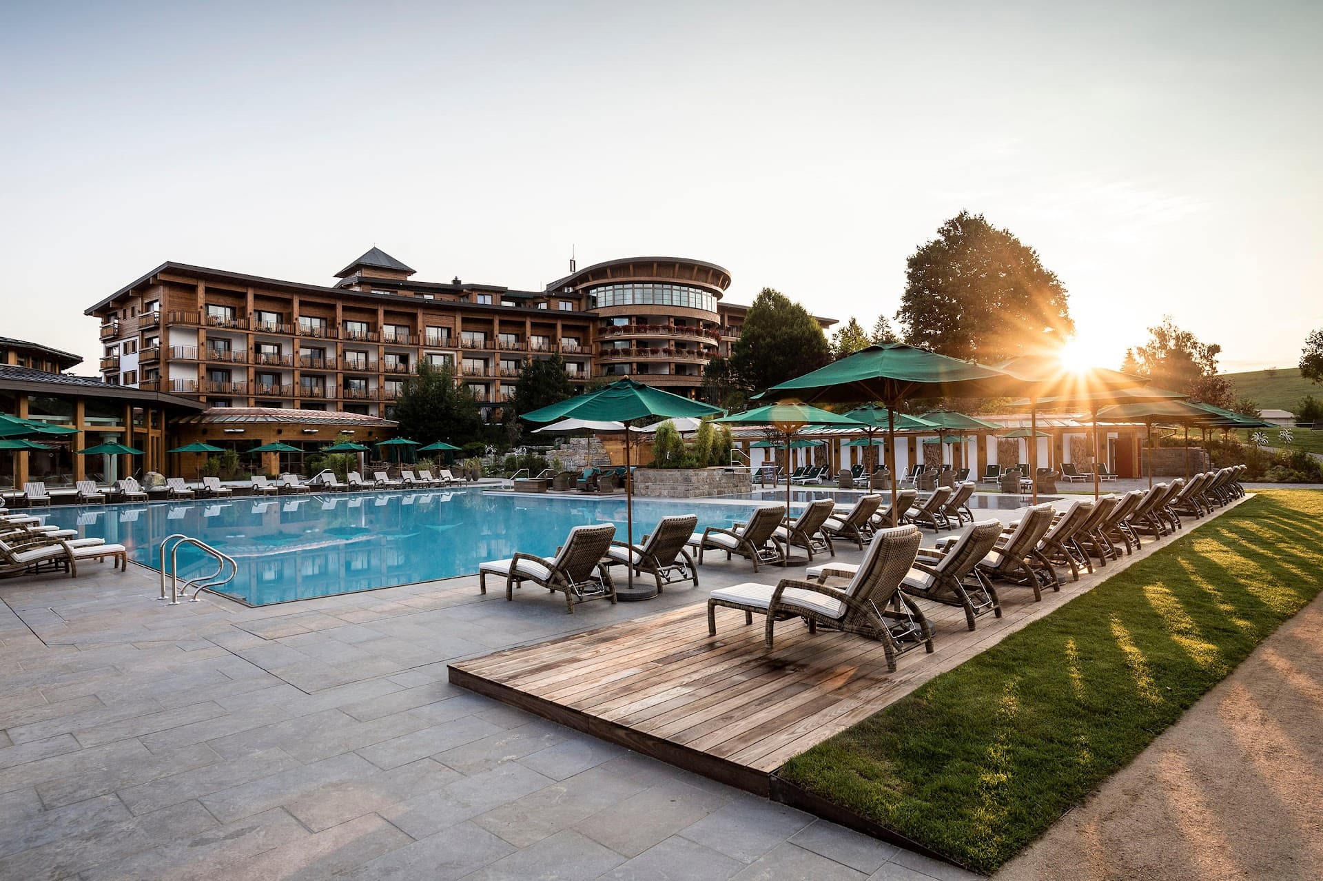 Západ slunce nad venkovním bazénem wellness hotelu Sonnenalp Resort v Allgäu, Německo