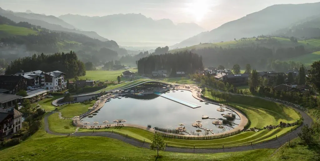 Naturalne jezioro i 50-metrowy basen infinity resortu Krallerhof ATMOSPHERE w Leogang o świcie