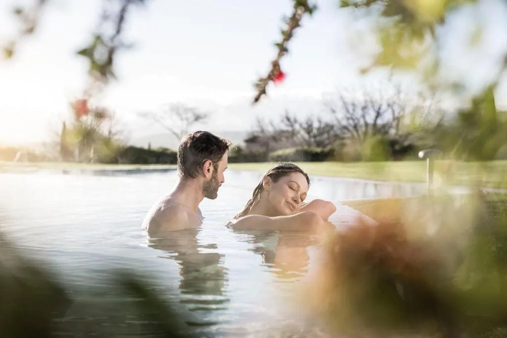Coppia che si rilassa nella piscina termale esterna dell'ADLER Spa Resort Thermae a Bagno Vignoni