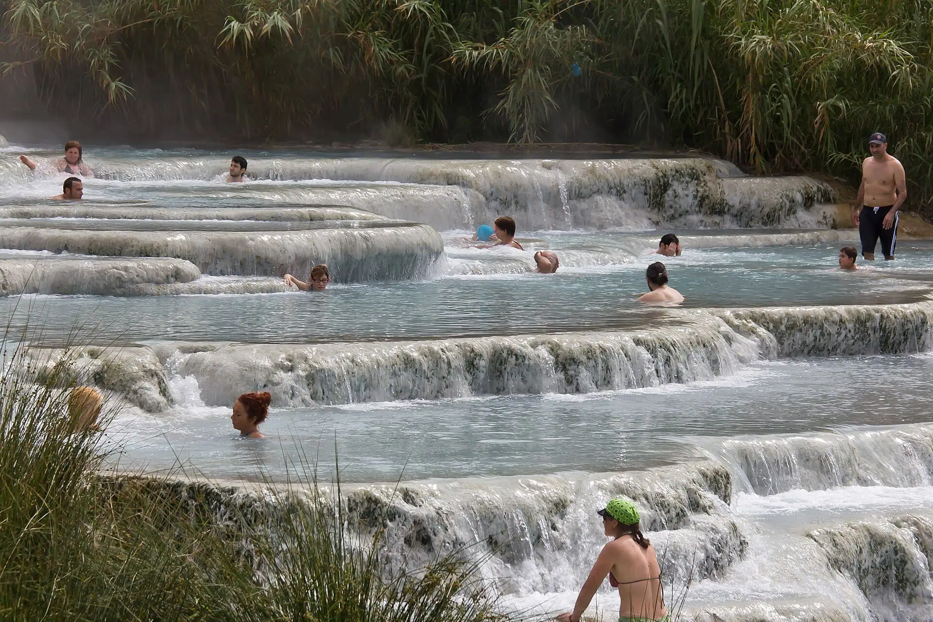 Persone che si immergono nelle cascate travertiniche delle Cascate del Mulino vicino a Saturnia