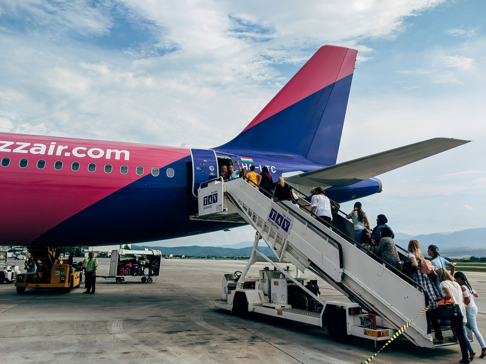 Unde să stai cu copilul în avion și ce se schimbă în 2026 3 Pasageri urcând în avion pe scări