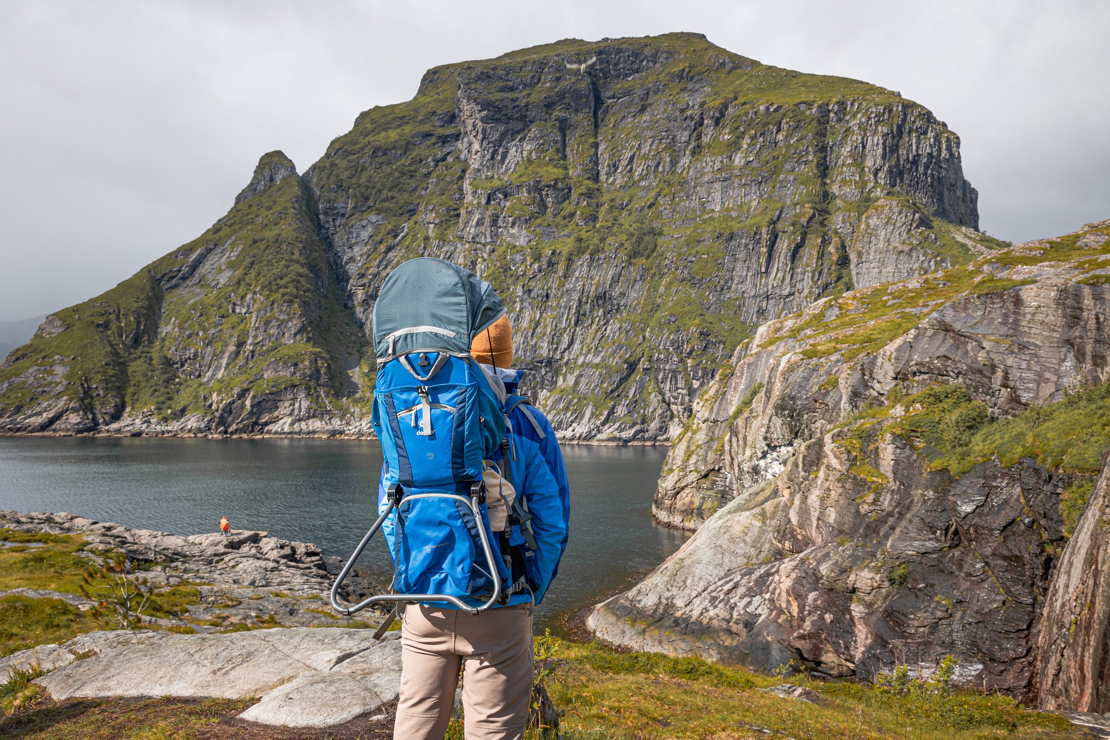 8 trasee și drumeții de neuitat în Insulele Lofoten (și pentru începători) 9 Turist cu un copil în marsupiu pe un traseu cu vedere spre fiord în Insulele Lofoten