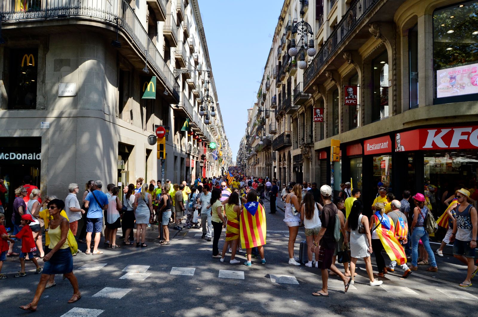 Retket Barcelonasta: 12 vinkkiä päiväretkeen 2026 4 Ihmisiä katalonialaislippujen kanssa Barcelonan kaduilla