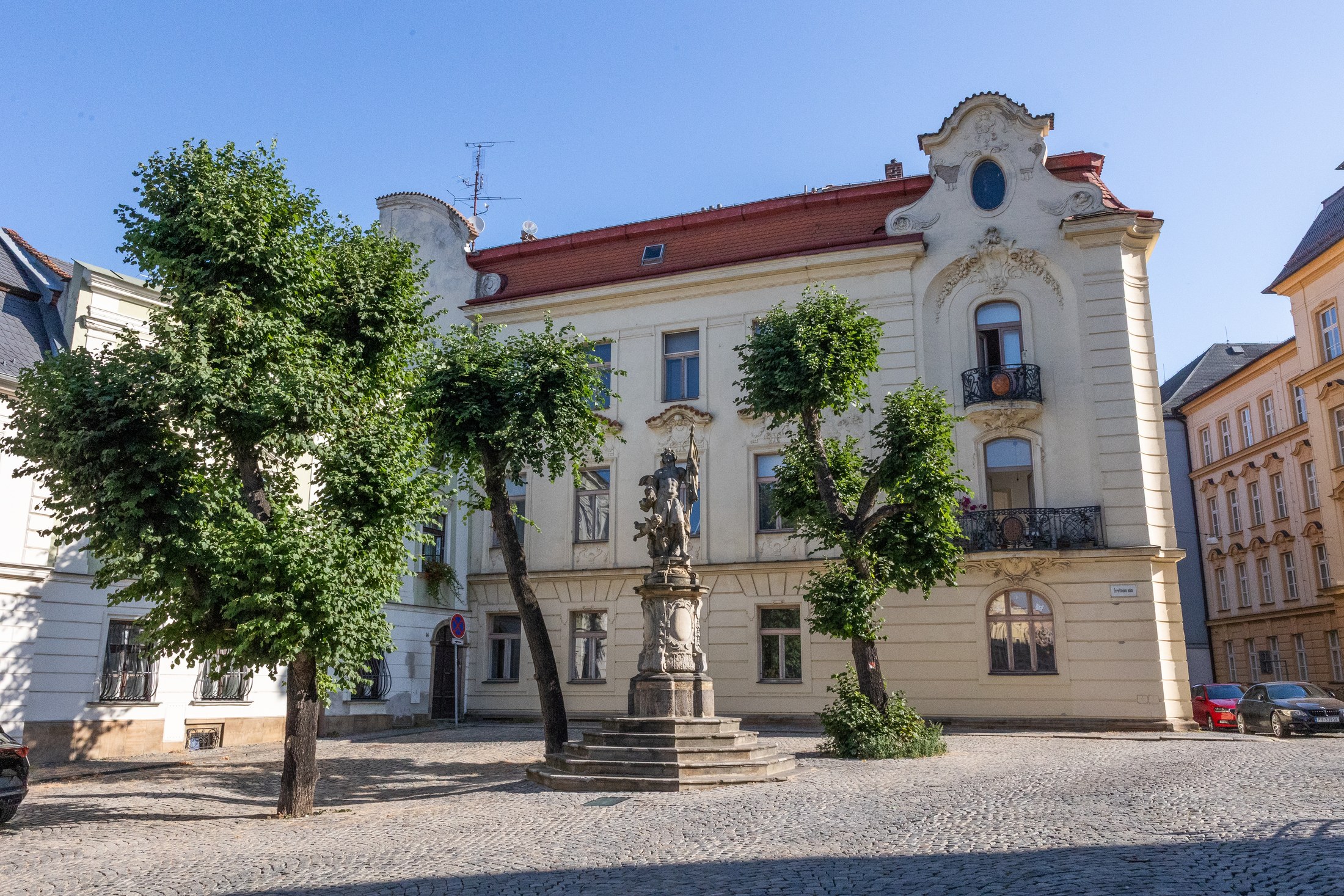 Olomouc con bambini: 34 idee su cosa fare e dove andare nel 2026 2 Casa barocca e statua nella piazza di Olomouc con alberi