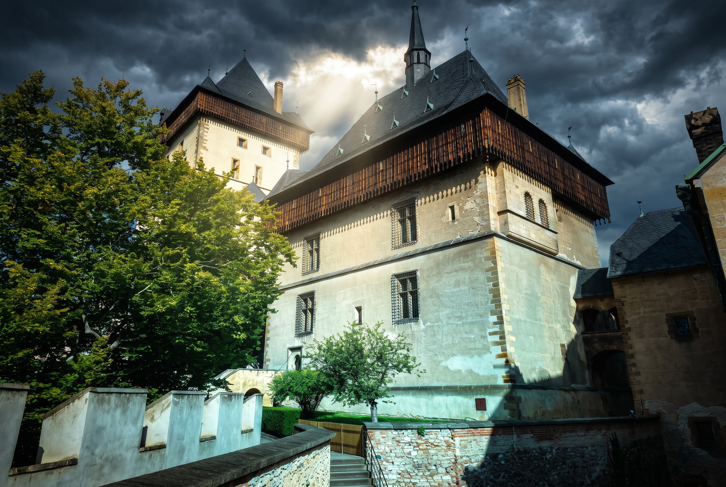 Gotické hradby a Císařský palác Karlštejna pod dramatickou oblohou