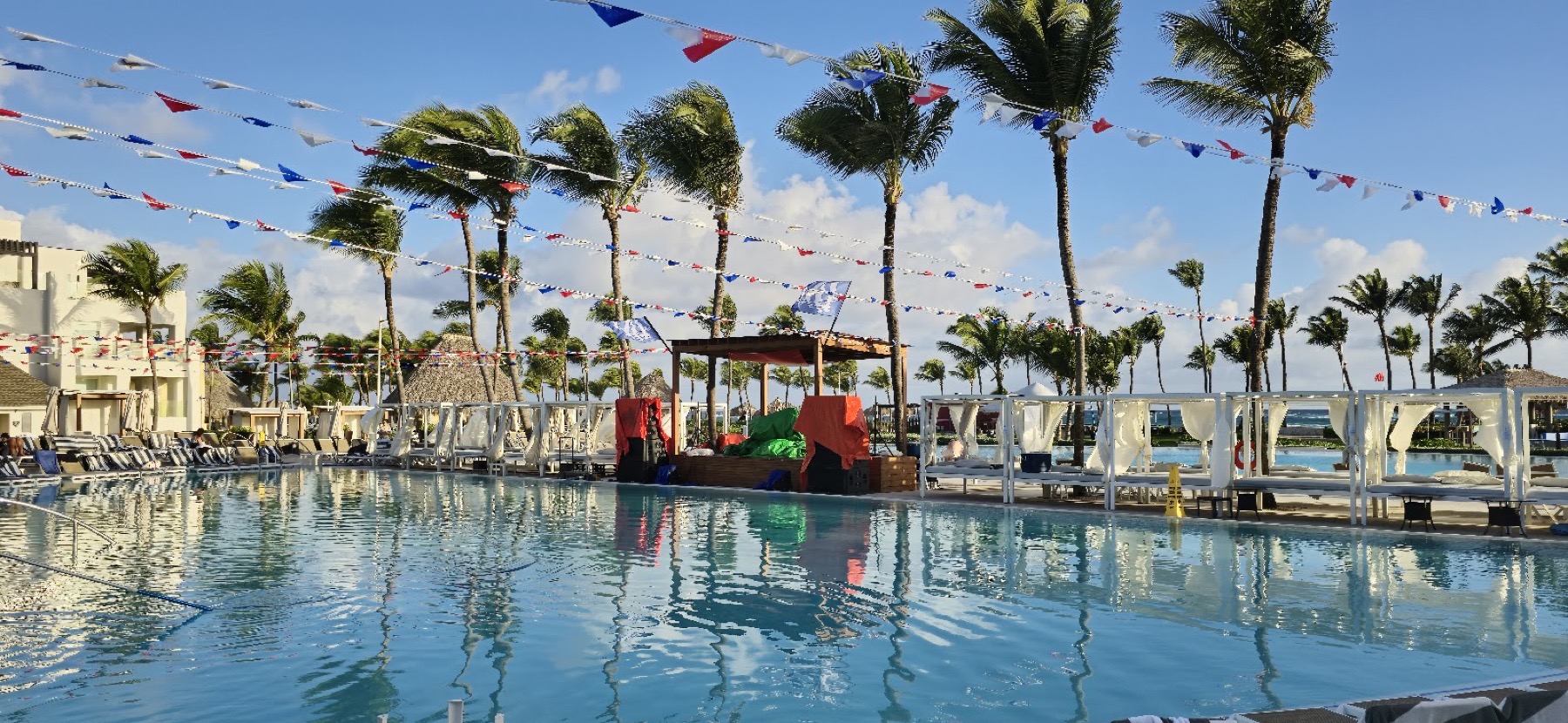 Hlavní bazén resortu Hard Rock Punta Cana s palmami a dominikánskými vlaječkami